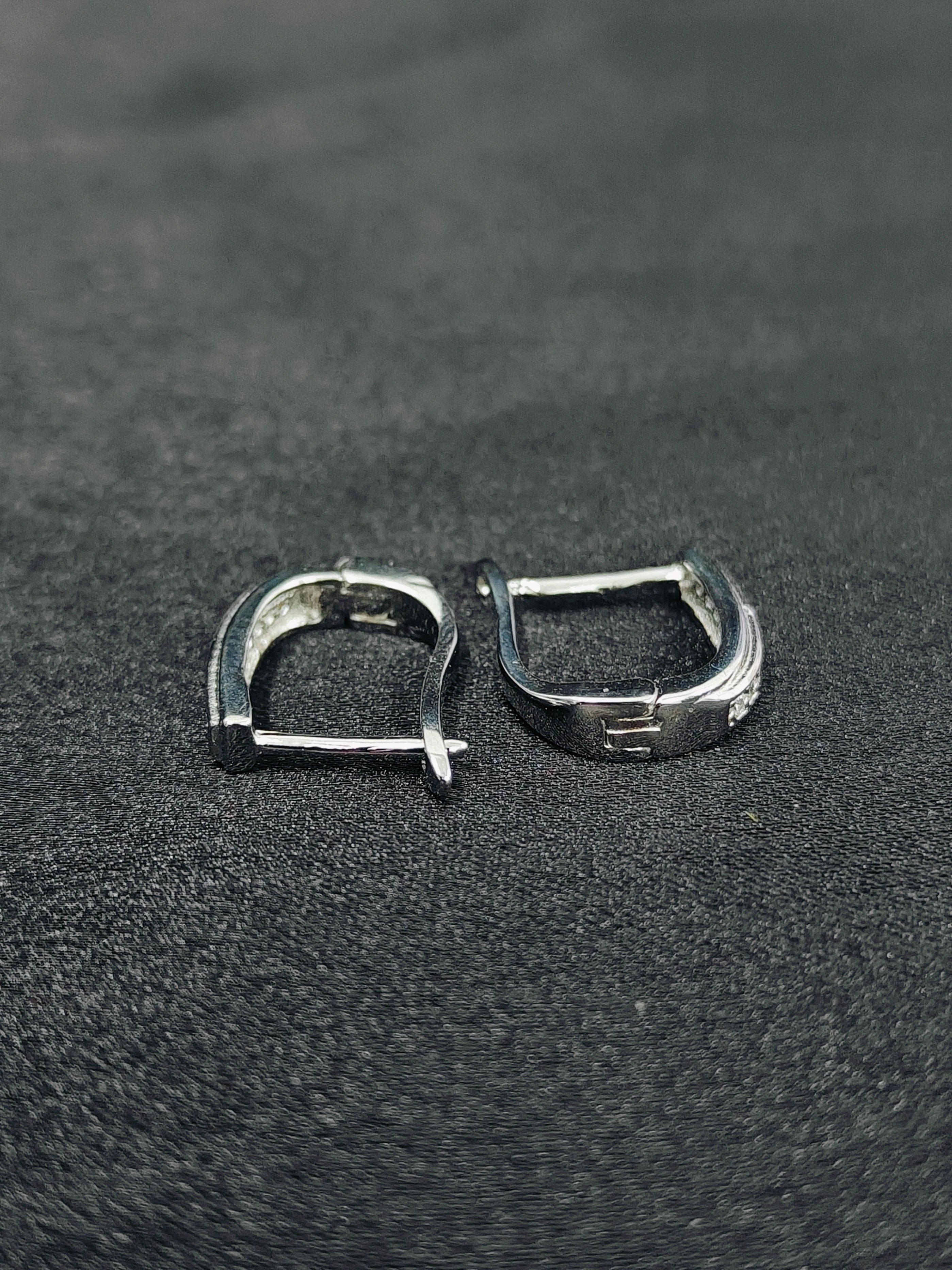 Pair of silver hoop earrings on a black textured surface