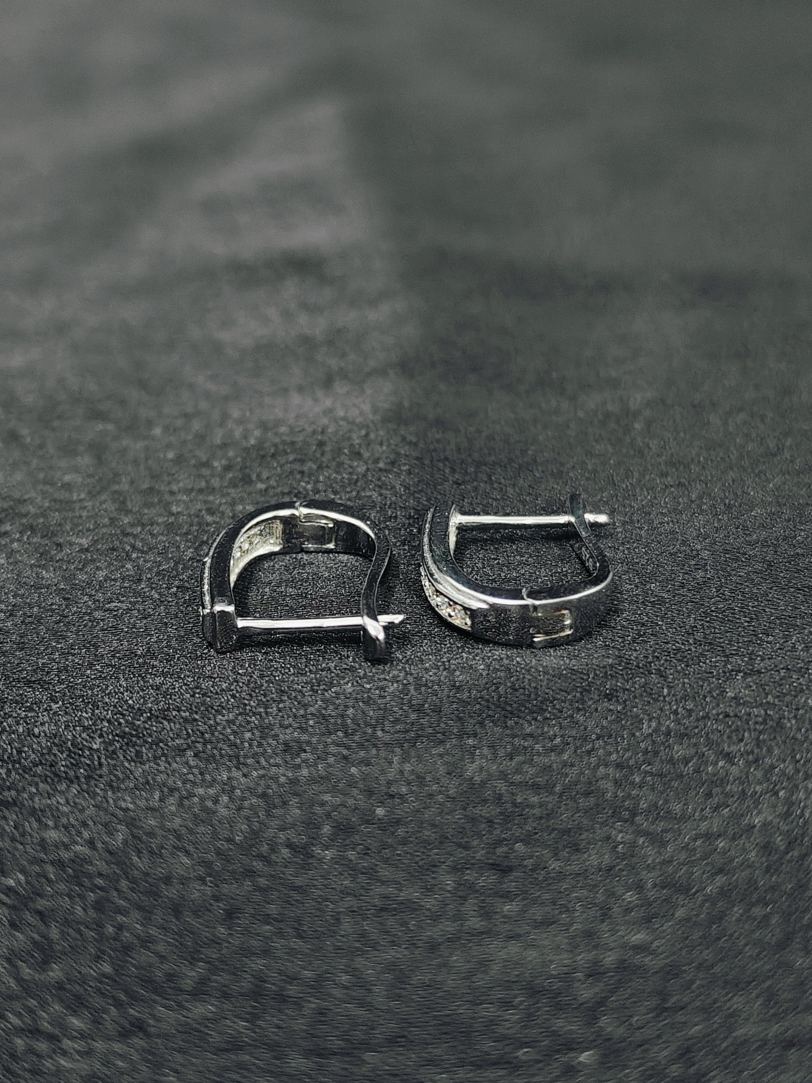 Two silver hoop earrings on a textured black surface