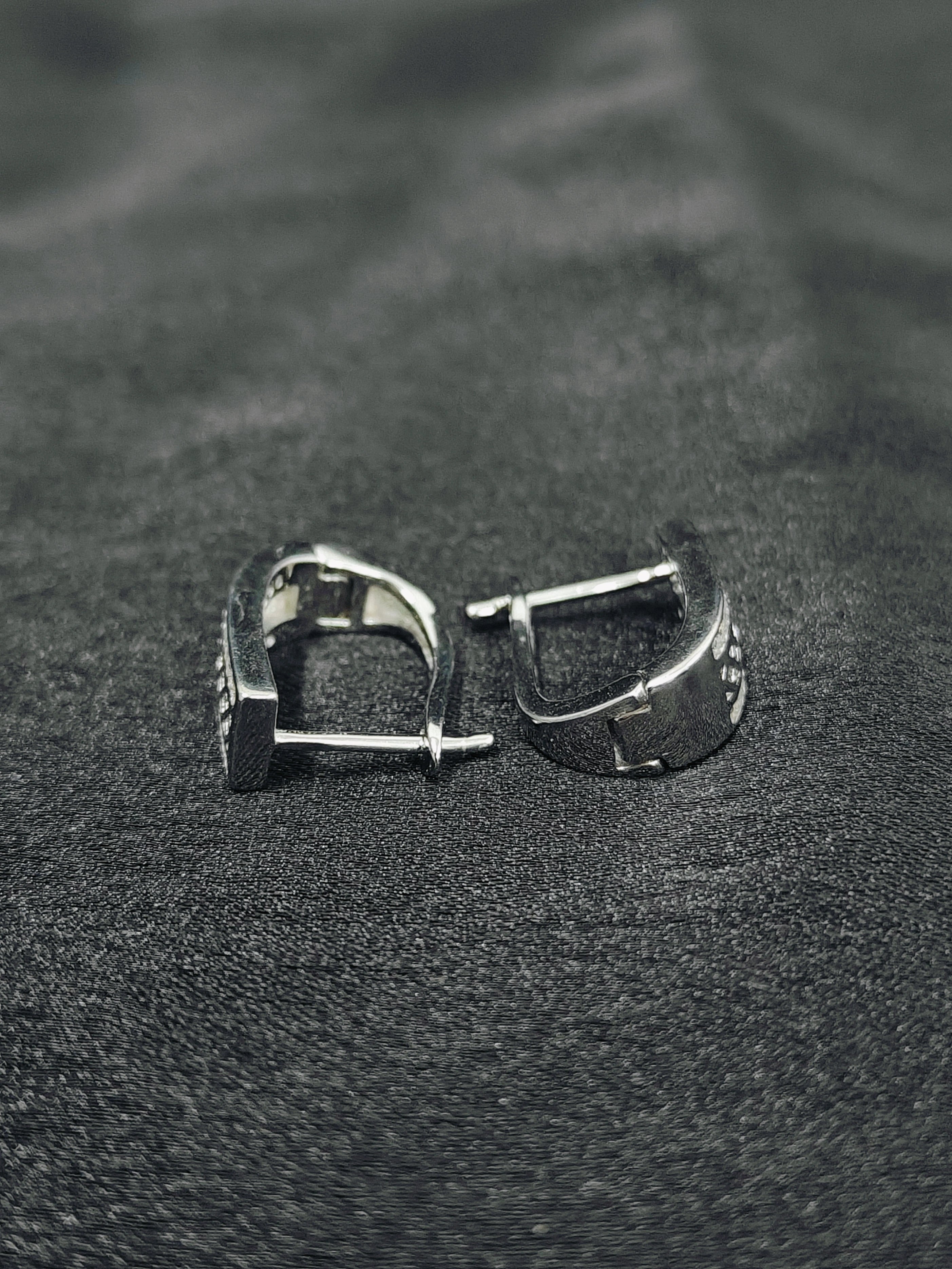 Silver hoop earrings on a textured black surface