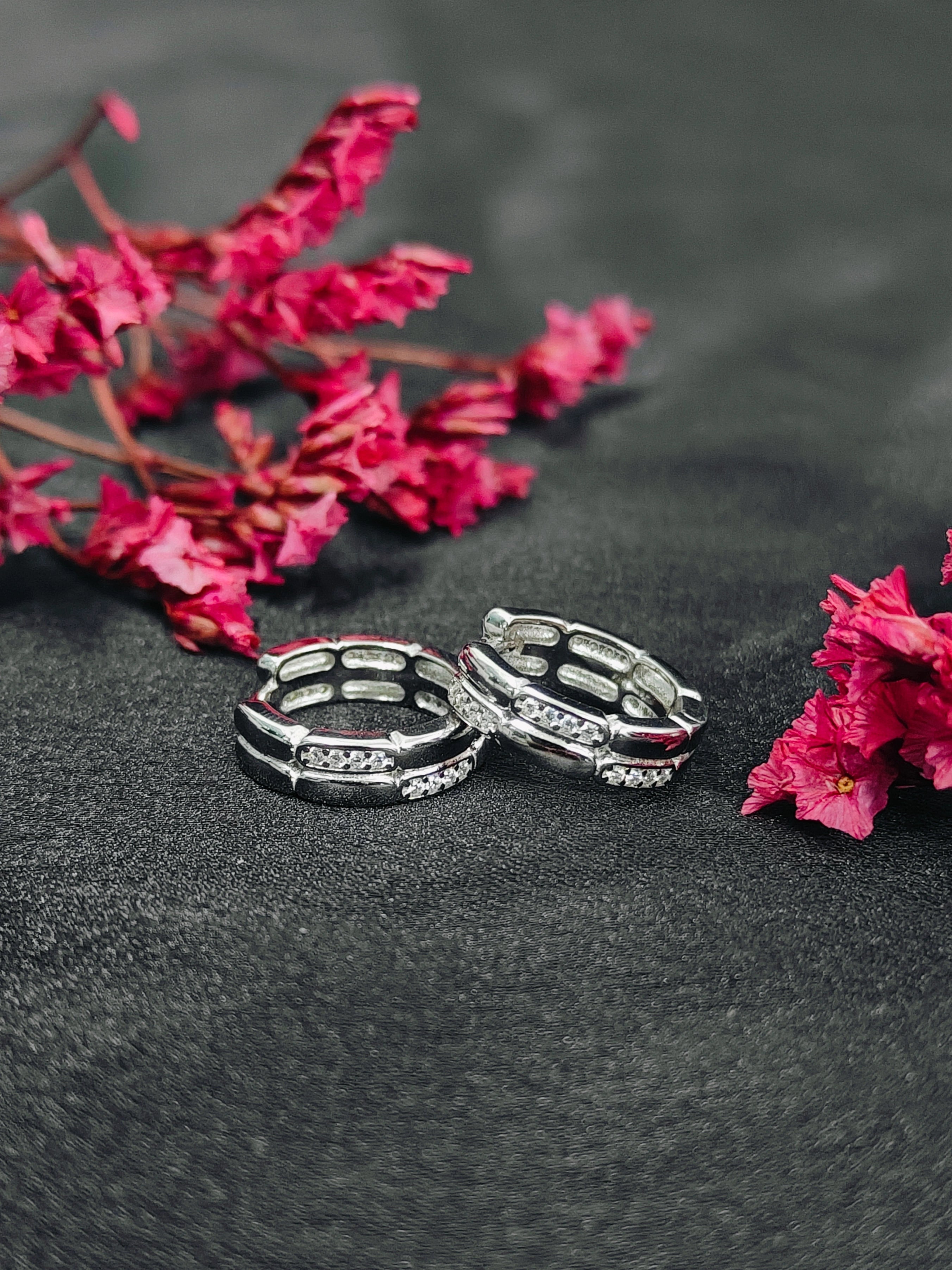 Two silver rings on a dark surface with pink flowers.