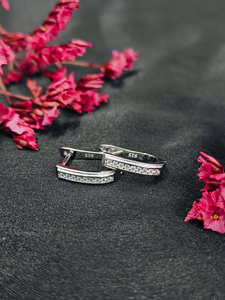 Silver rings with embedded stones on a dark surface with pink flowers.