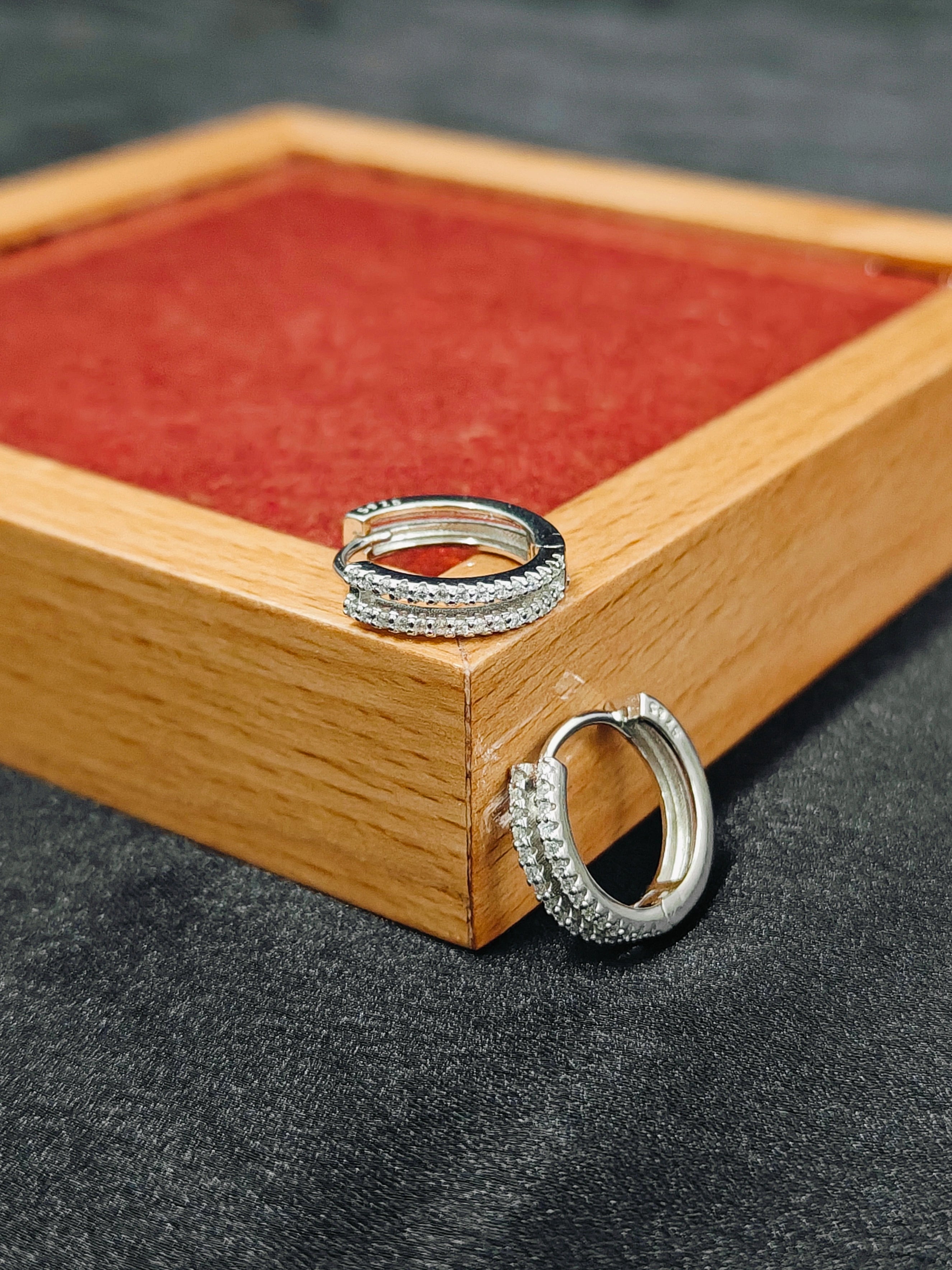 Silver rings on a wooden stand with a red fabric background