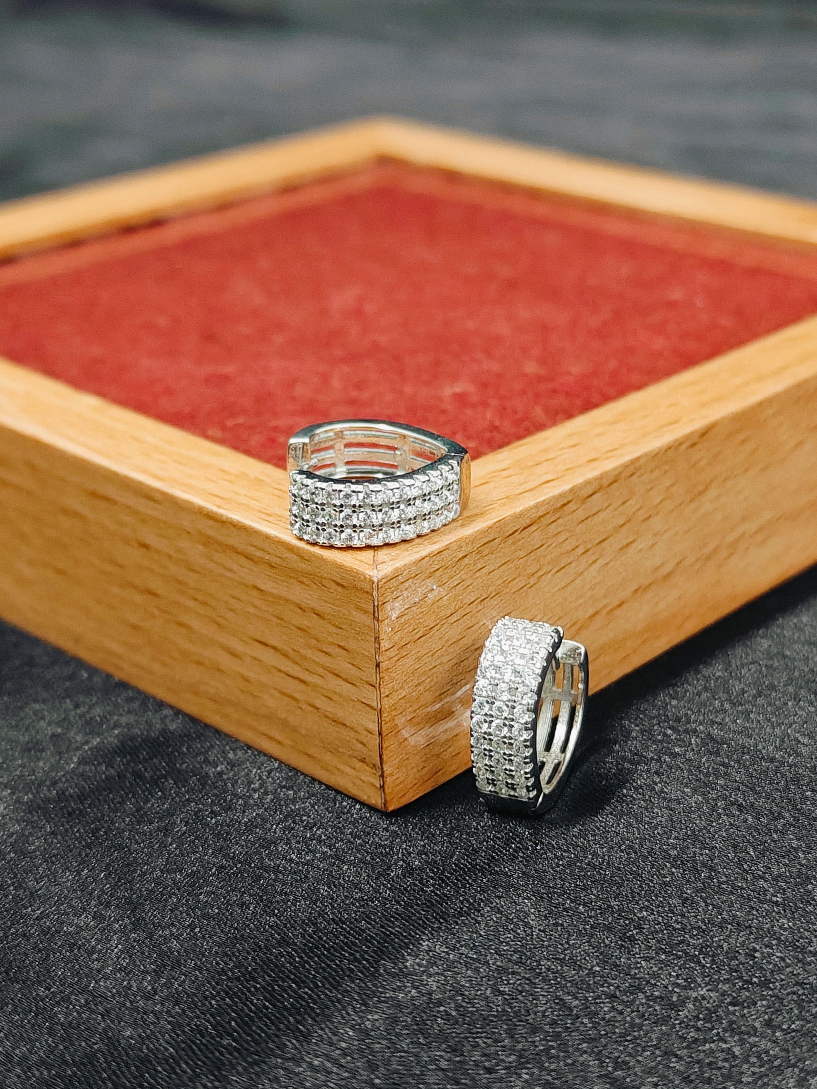 Silver hoop earrings on a wooden tray with red fabric