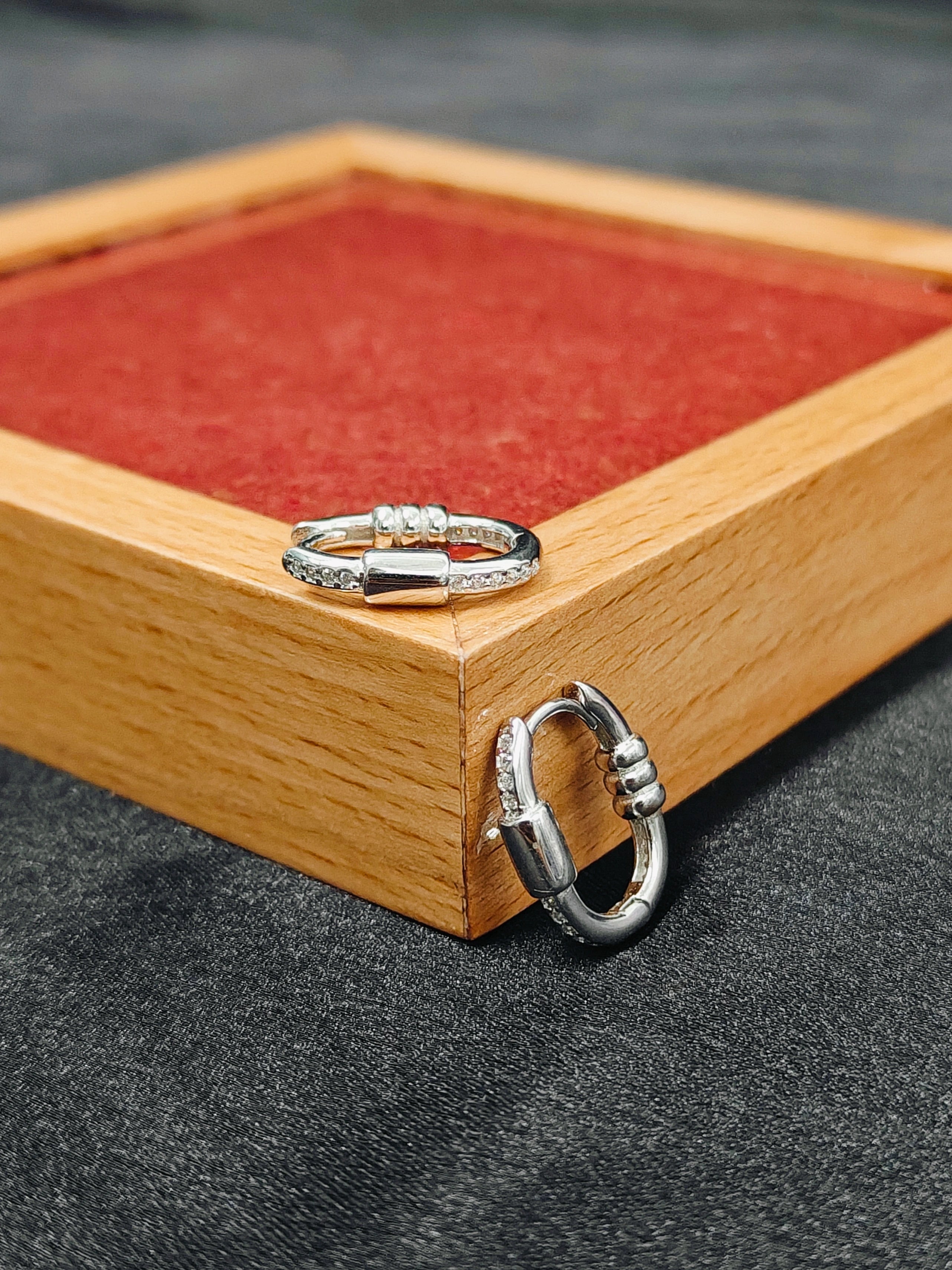 Silver ring on a wooden box with red fabric