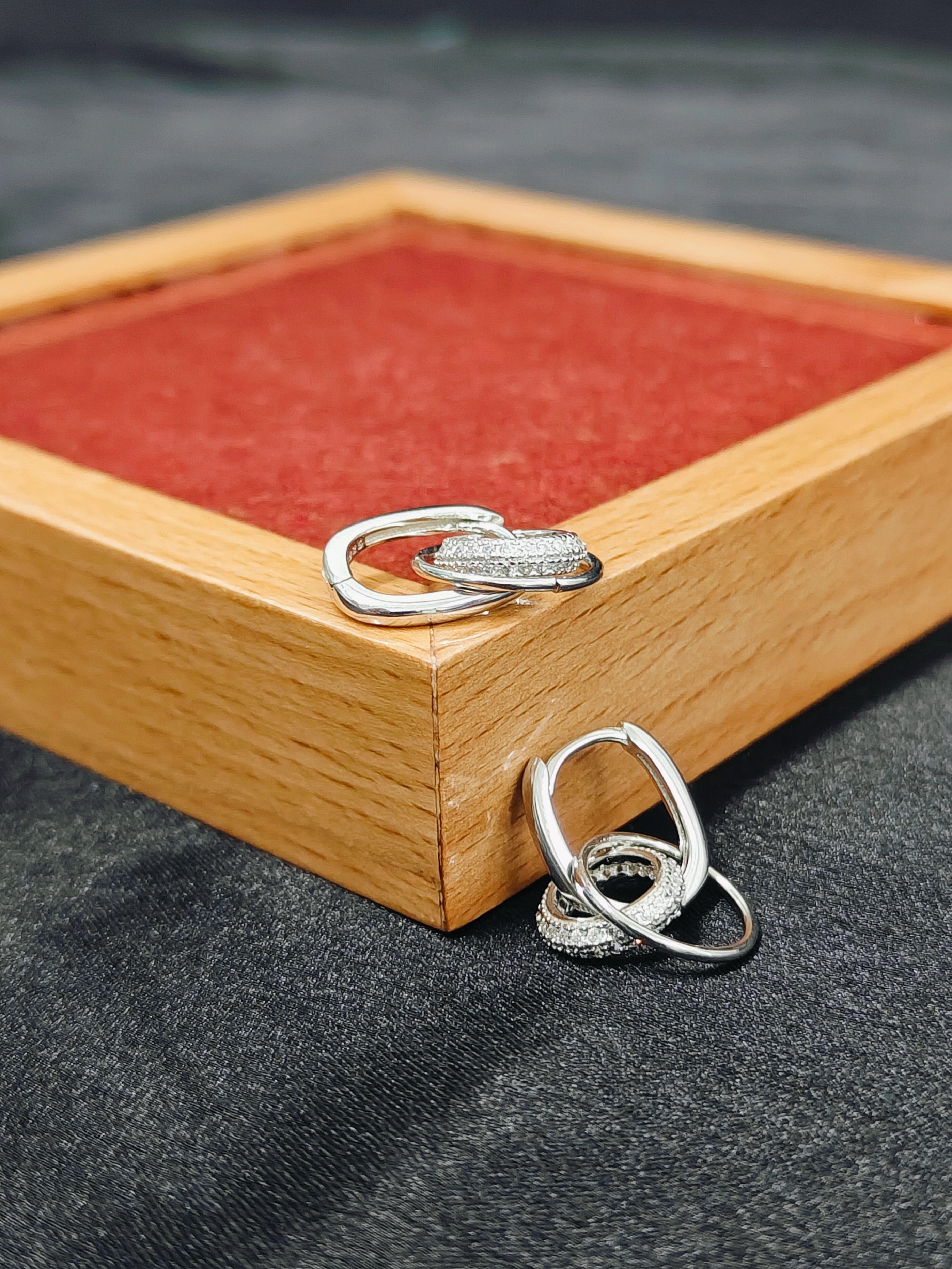 Silver rings on a wooden box with red interior