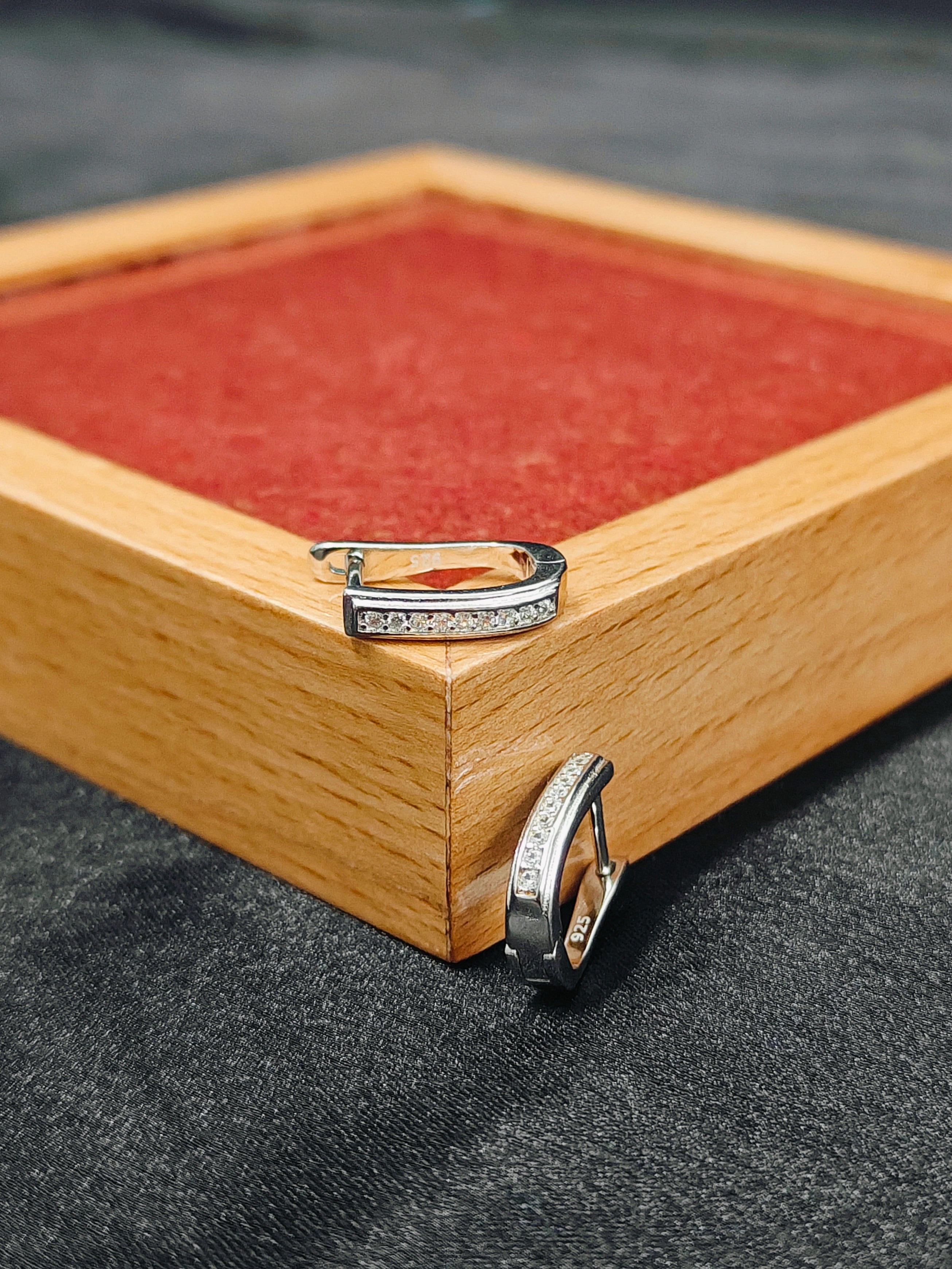 Two diamond rings on a wooden box with a red interior.