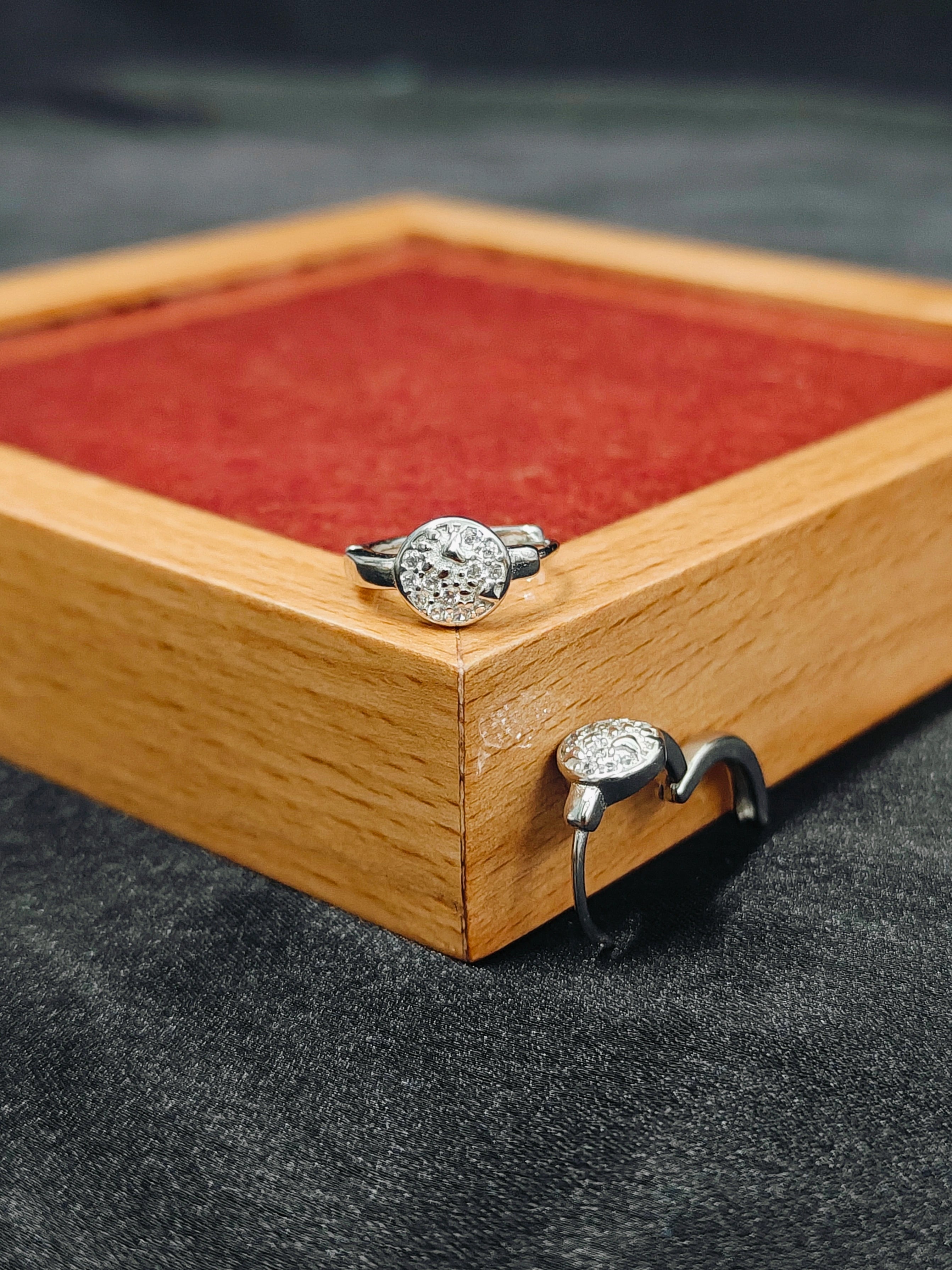 Two silver rings on a wooden display box with red fabric lining.