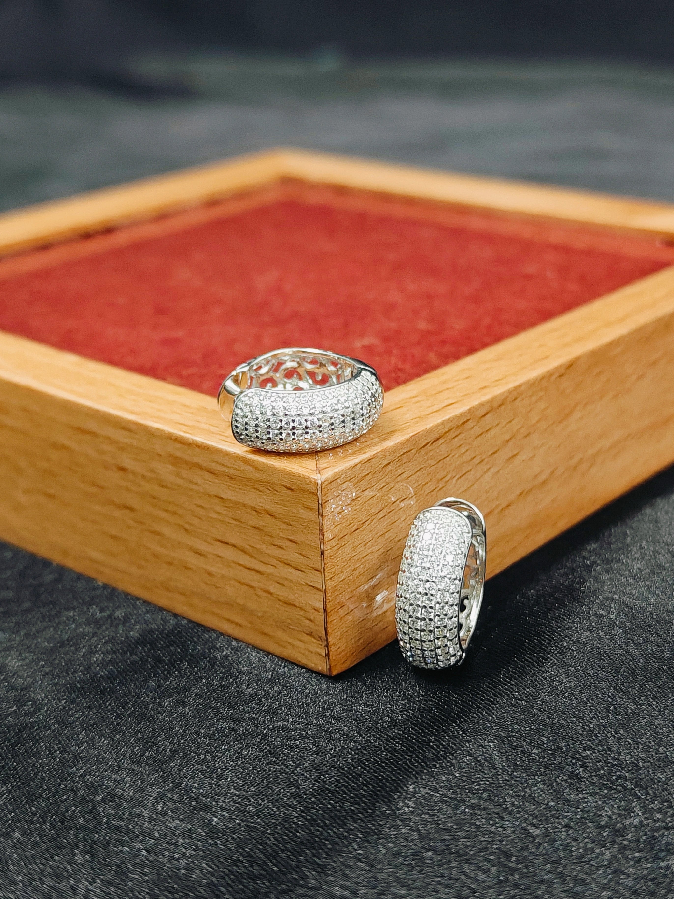 Silver hoop earrings on a wooden display box with red fabric