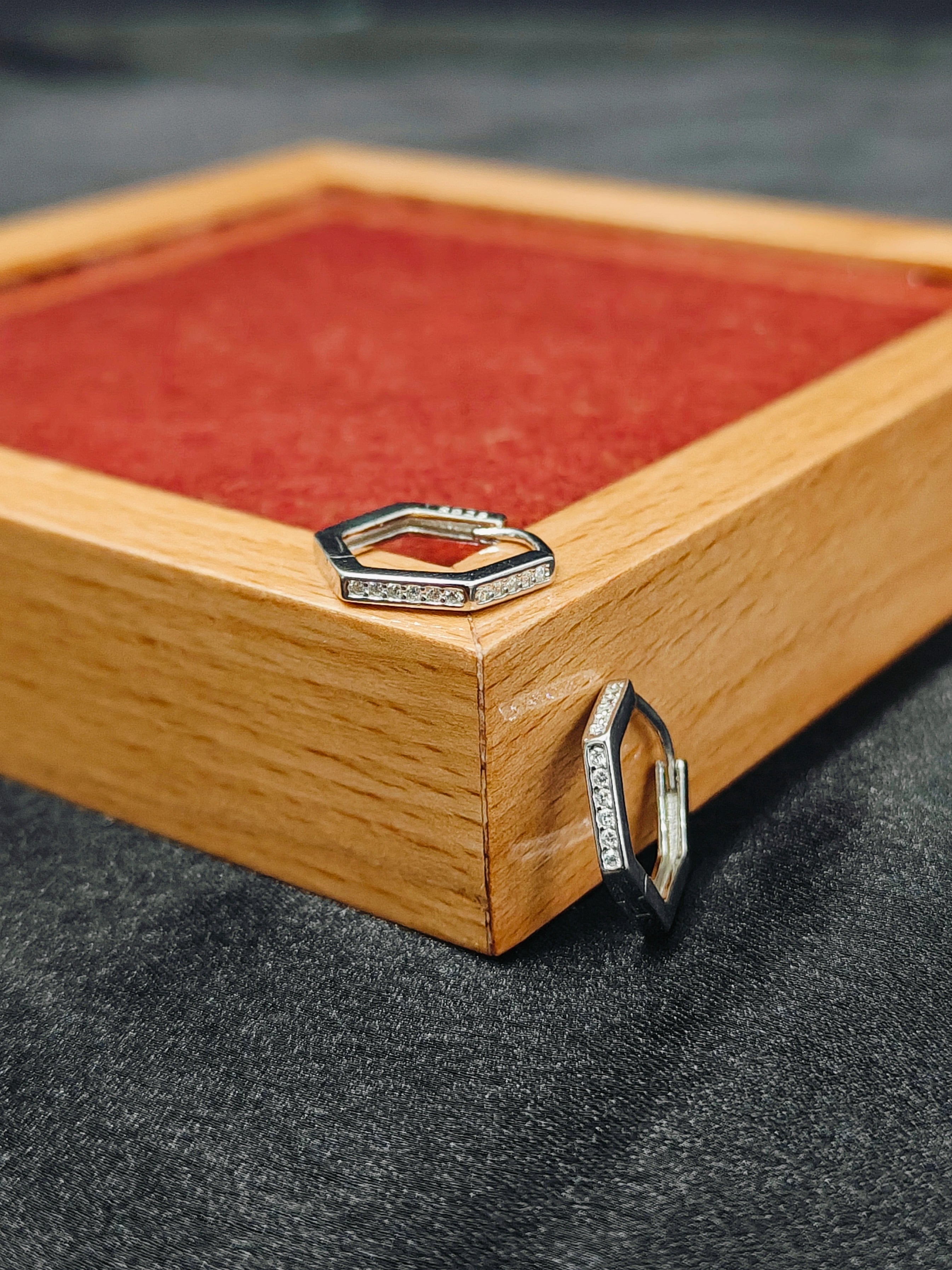 Two hexagonal rings on a wooden surface with a red fabric background