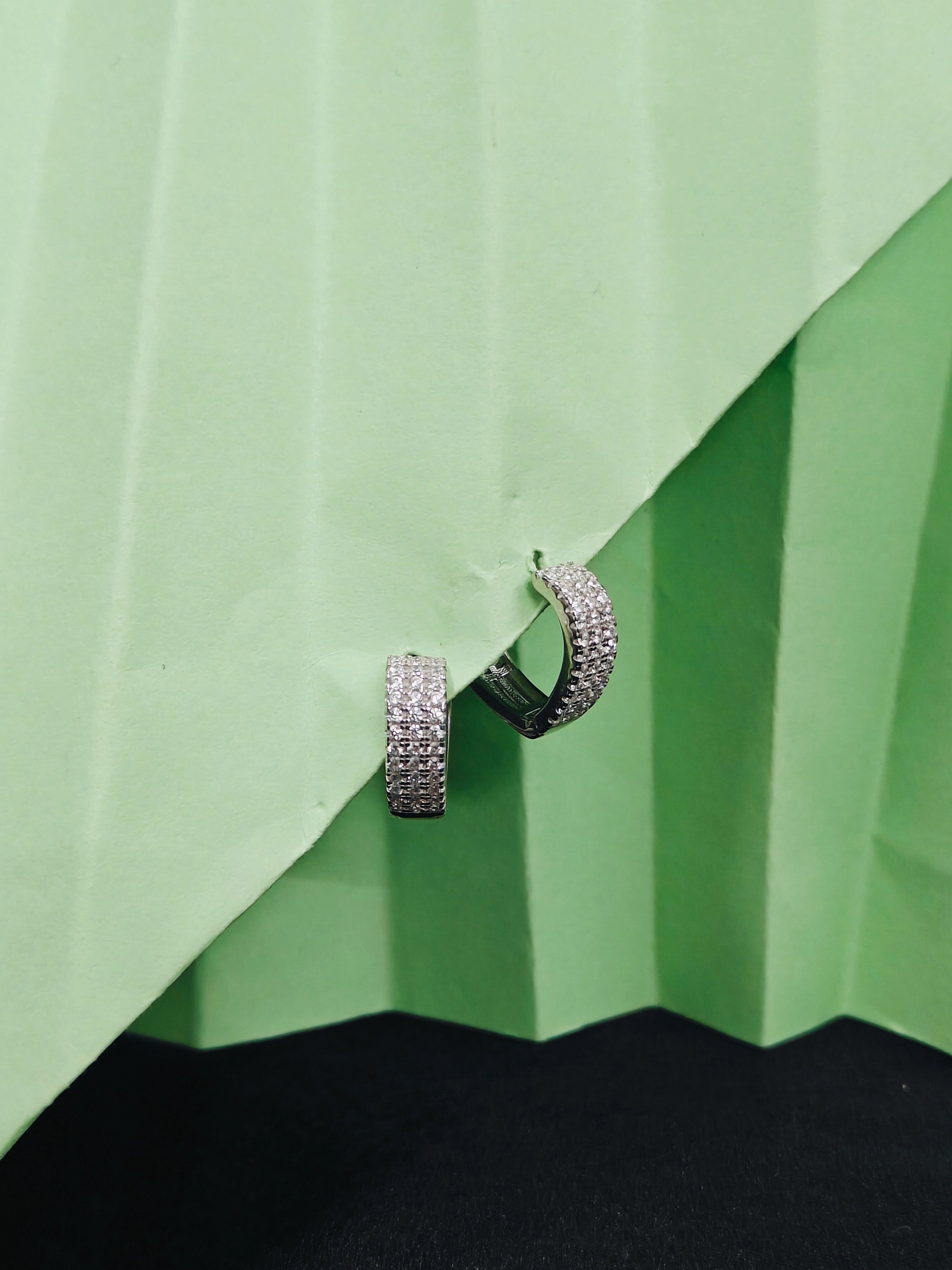 Silver hoop earring on a green geometric background
