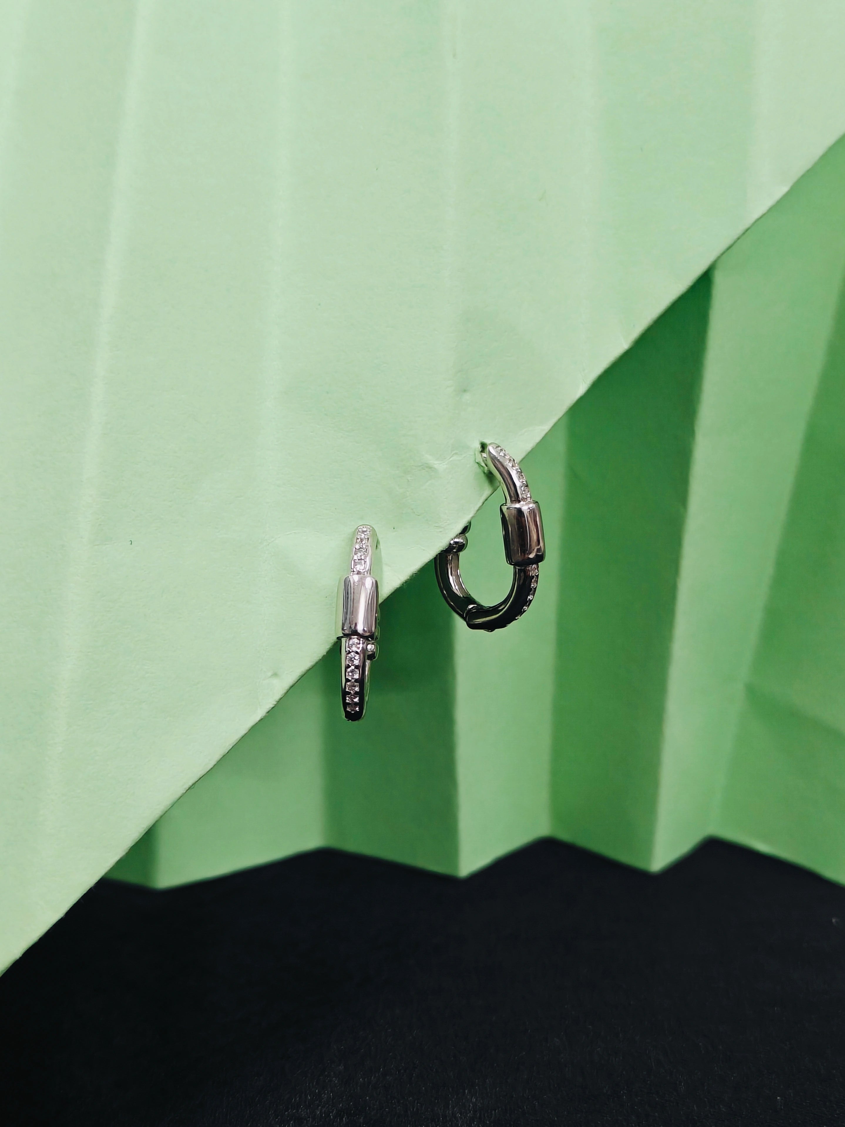 Two hoop earrings on a green and black geometric background