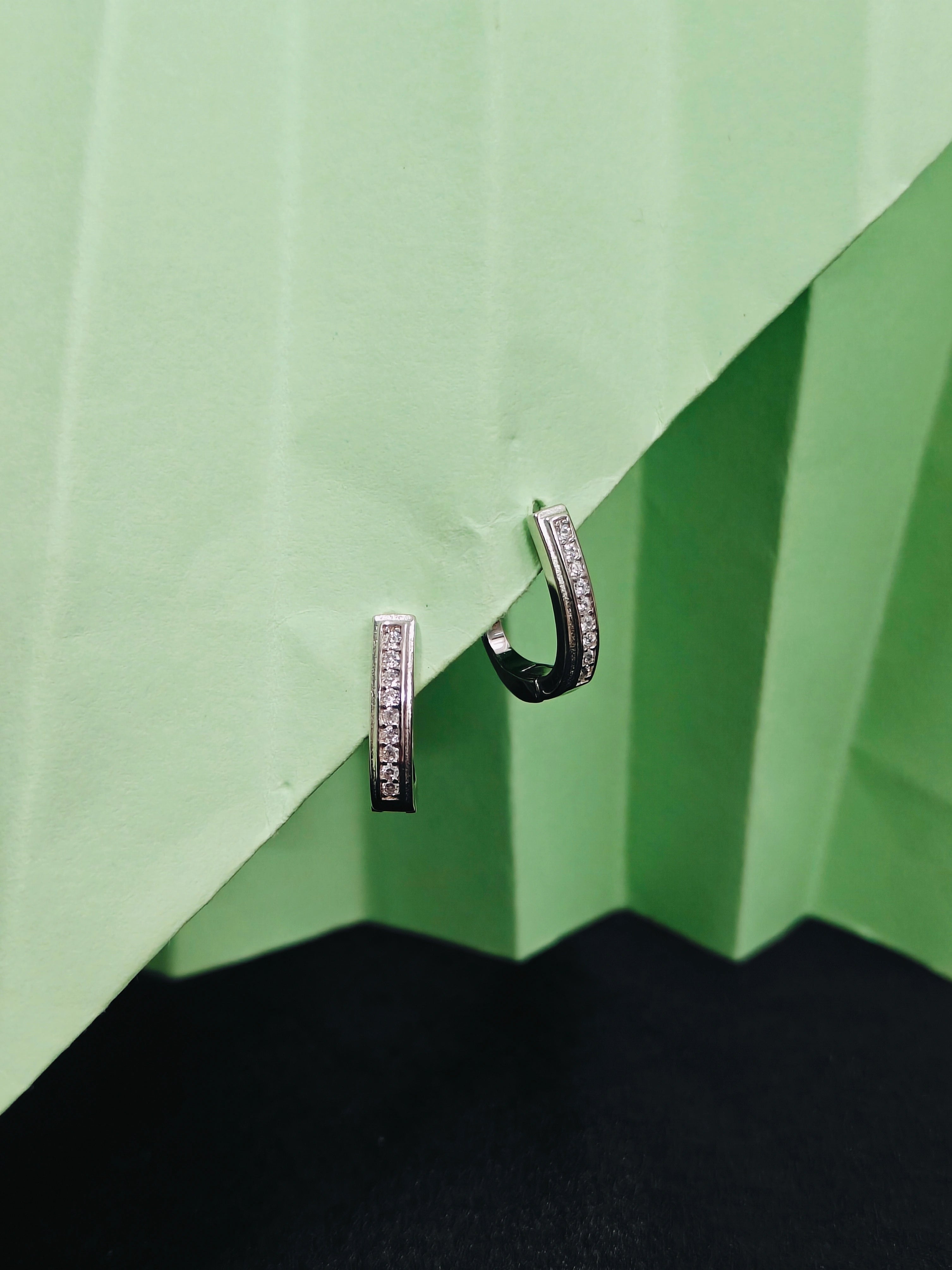Pair of hoop earrings on a green geometric background