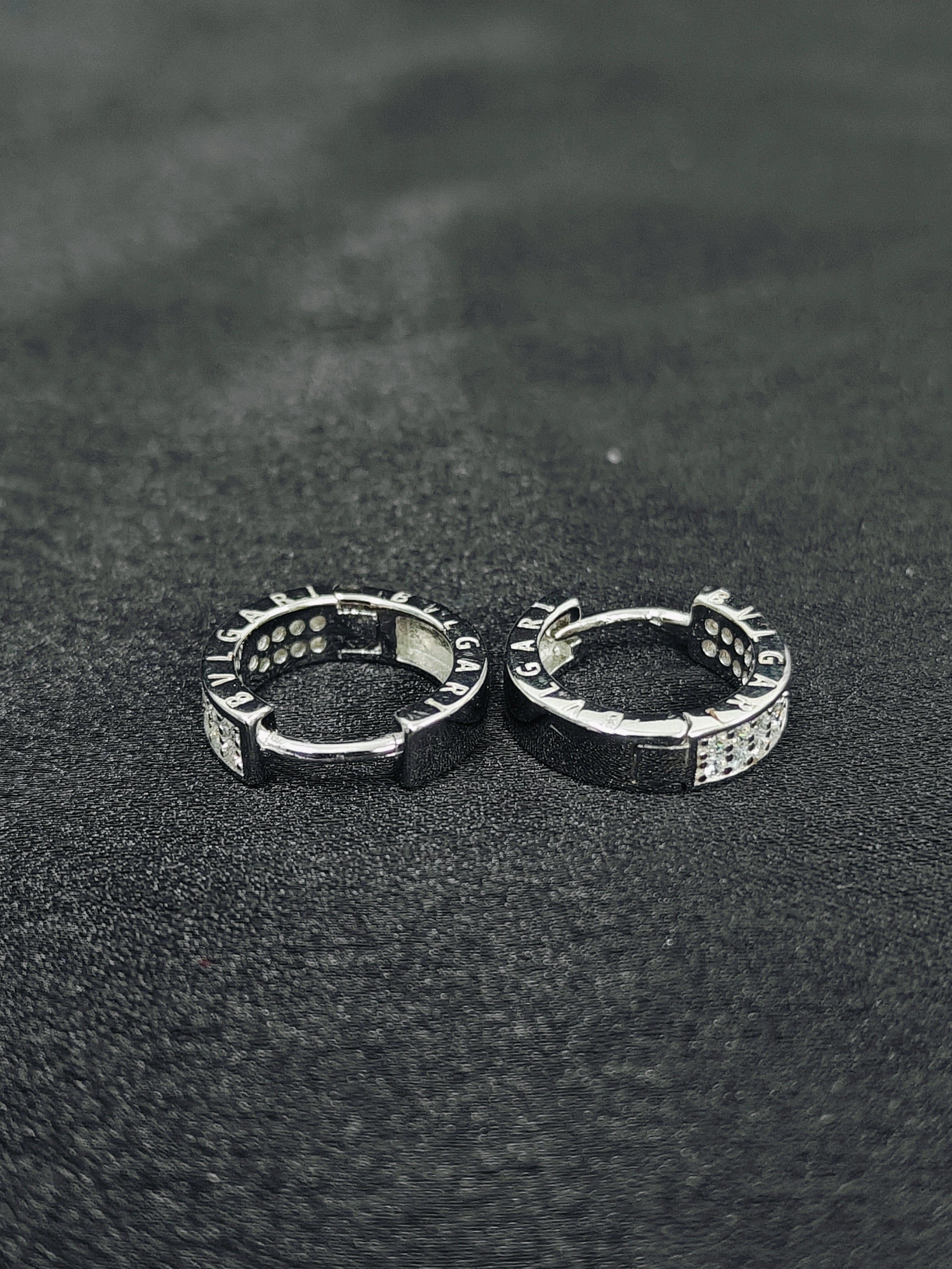 Pair of silver hoop earrings on a dark textured surface