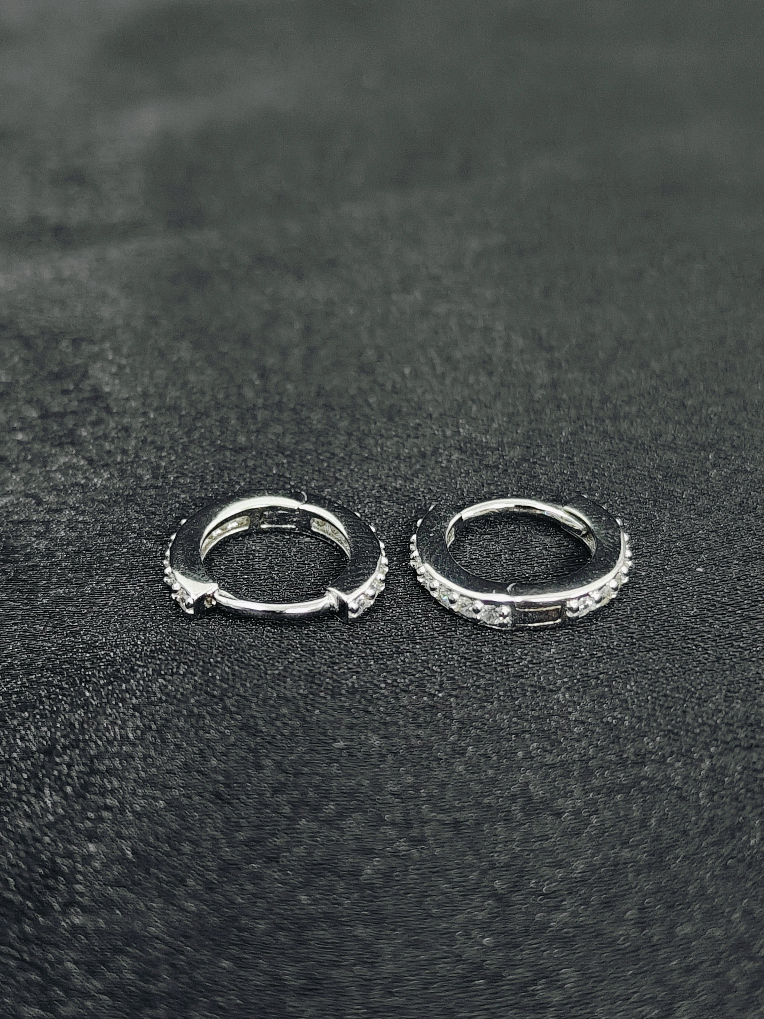 Pair of silver hoop earrings on a black textured surface