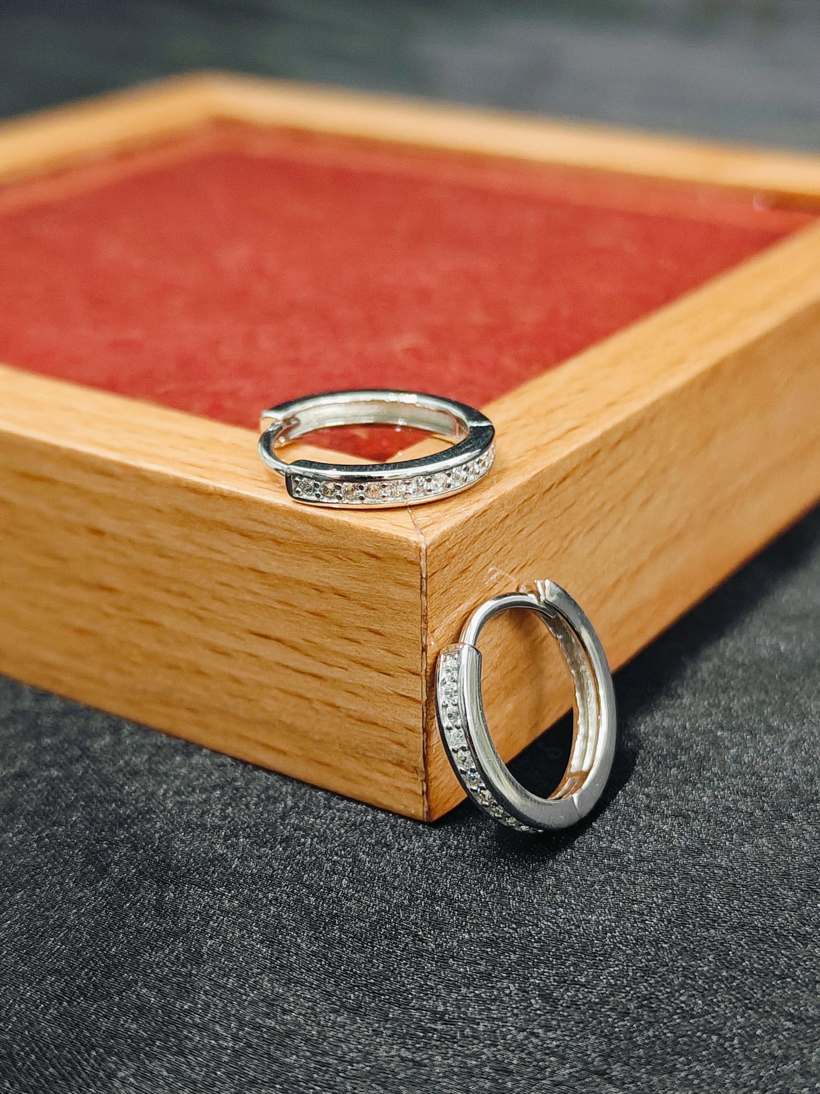 Two silver rings on a wooden box with a dark background