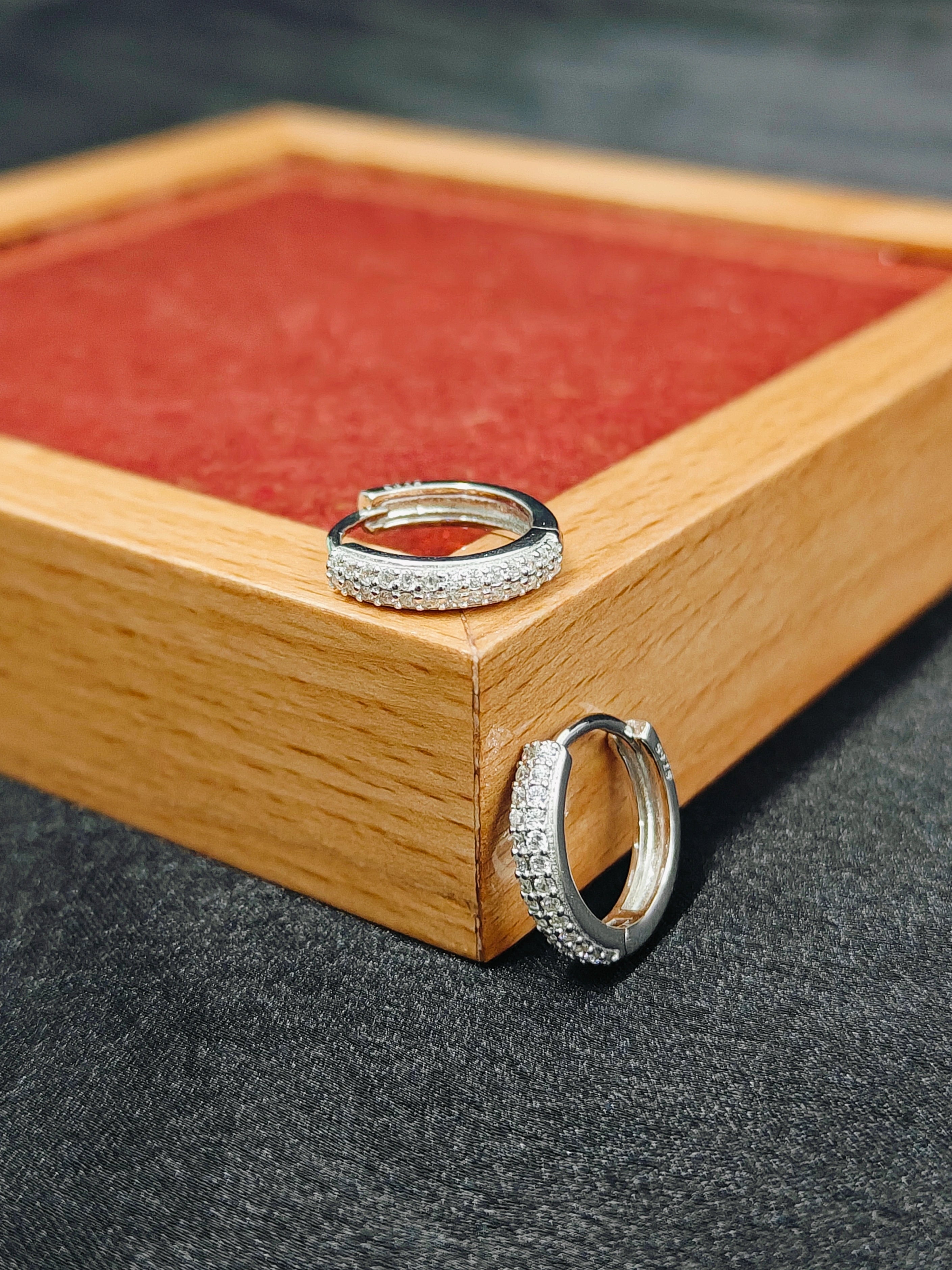 Silver hoop earrings on a wooden stand with a red cushion