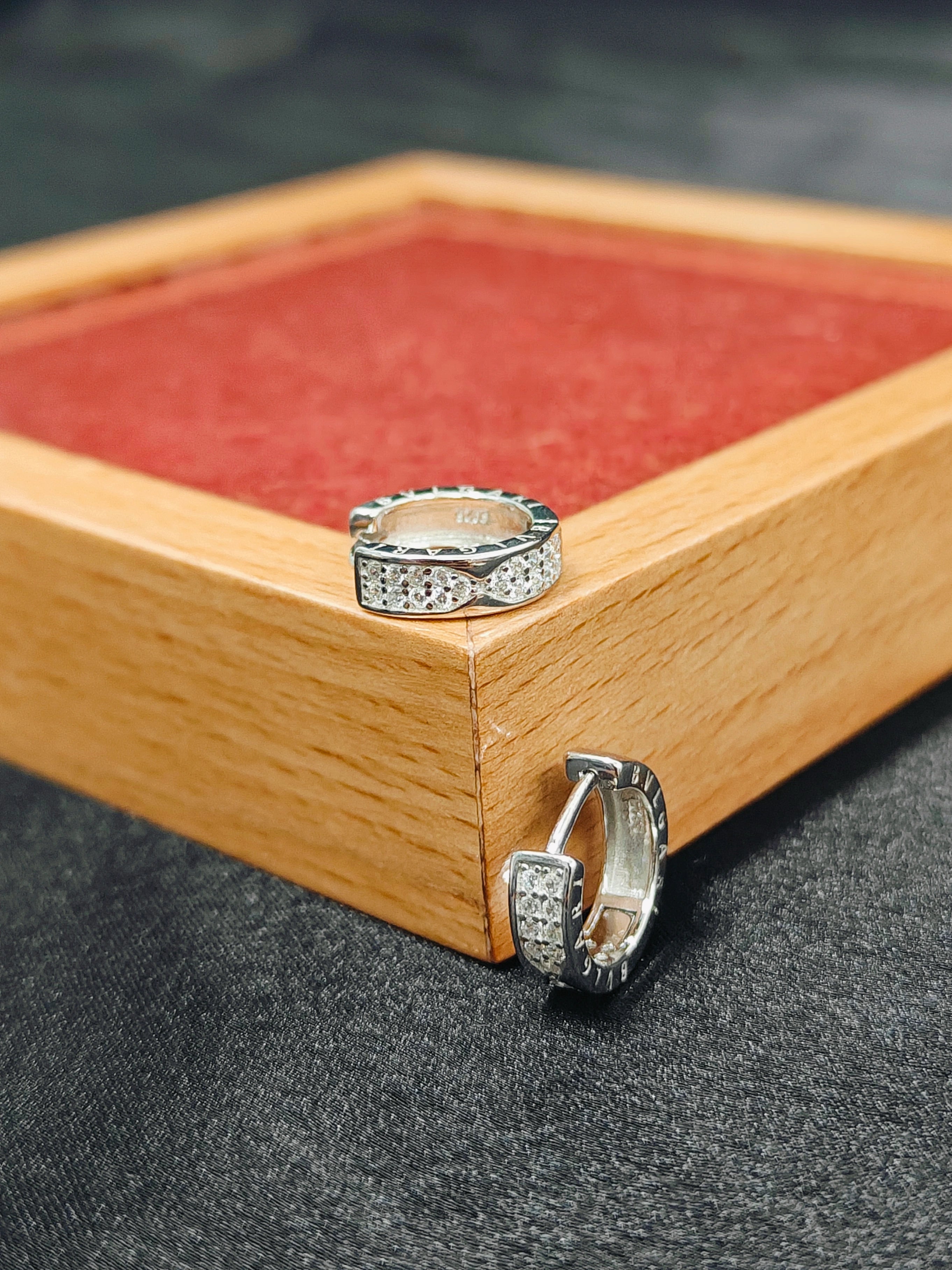 Two silver rings on a wooden box with a red interior.