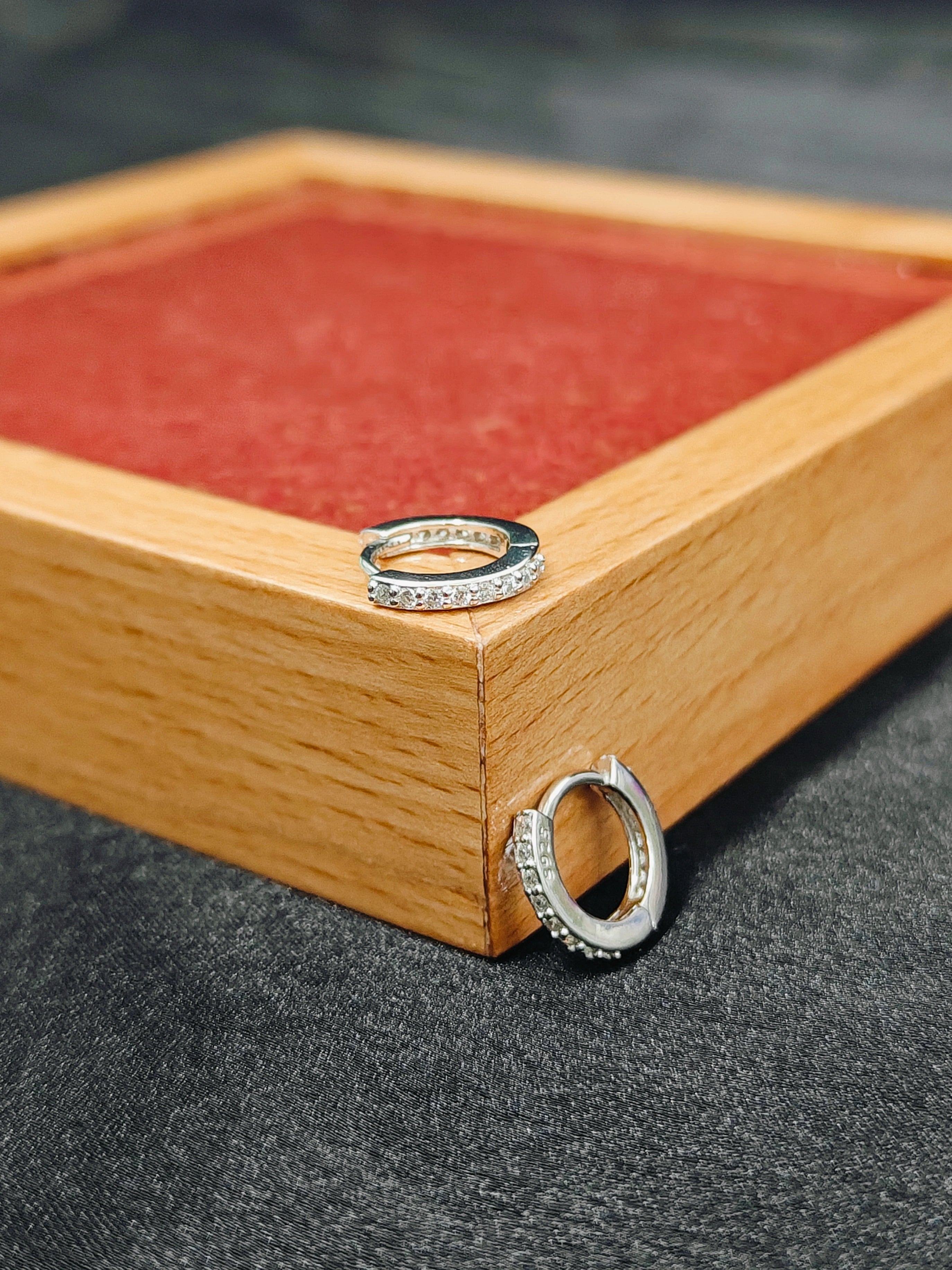 Silver rings on a wooden box with a red interior