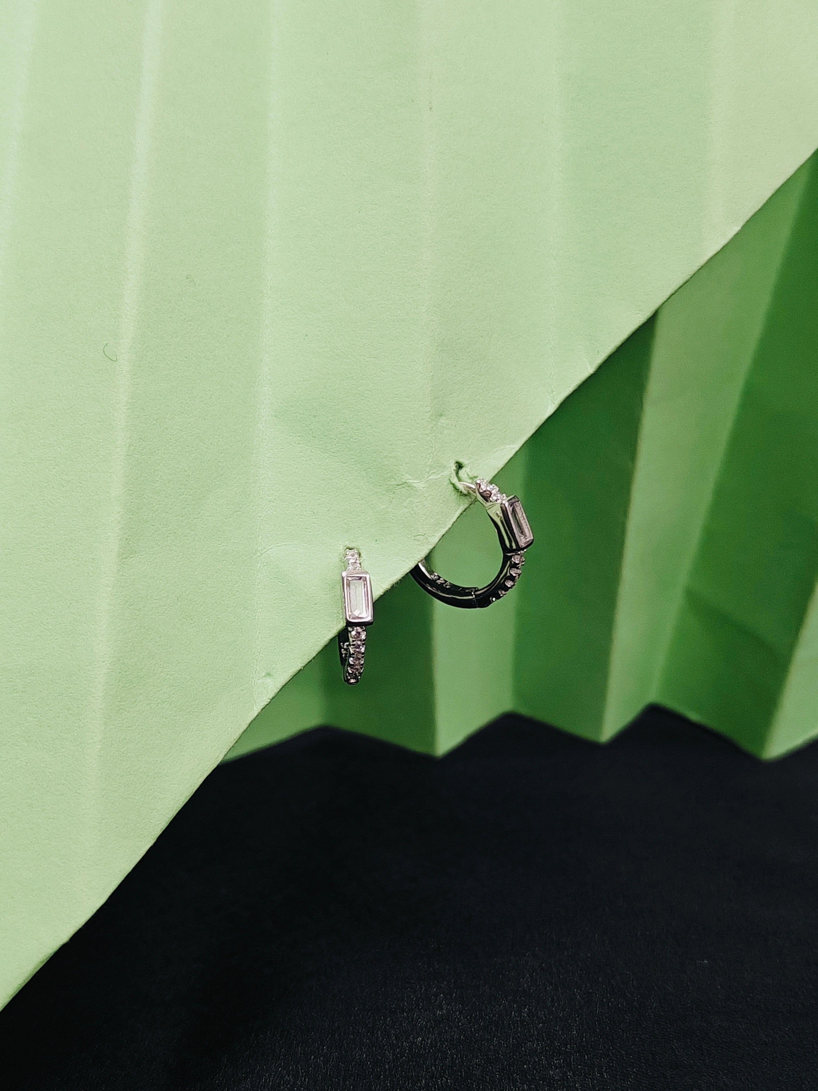 Pair of earrings on a green and black geometric background