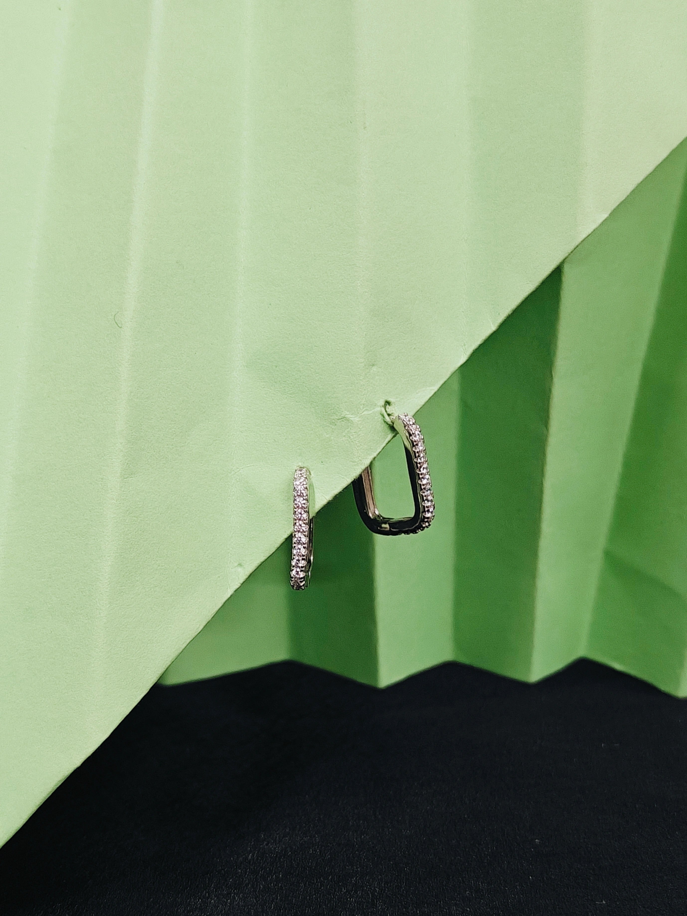 Two hoop earrings on a green and black textured surface