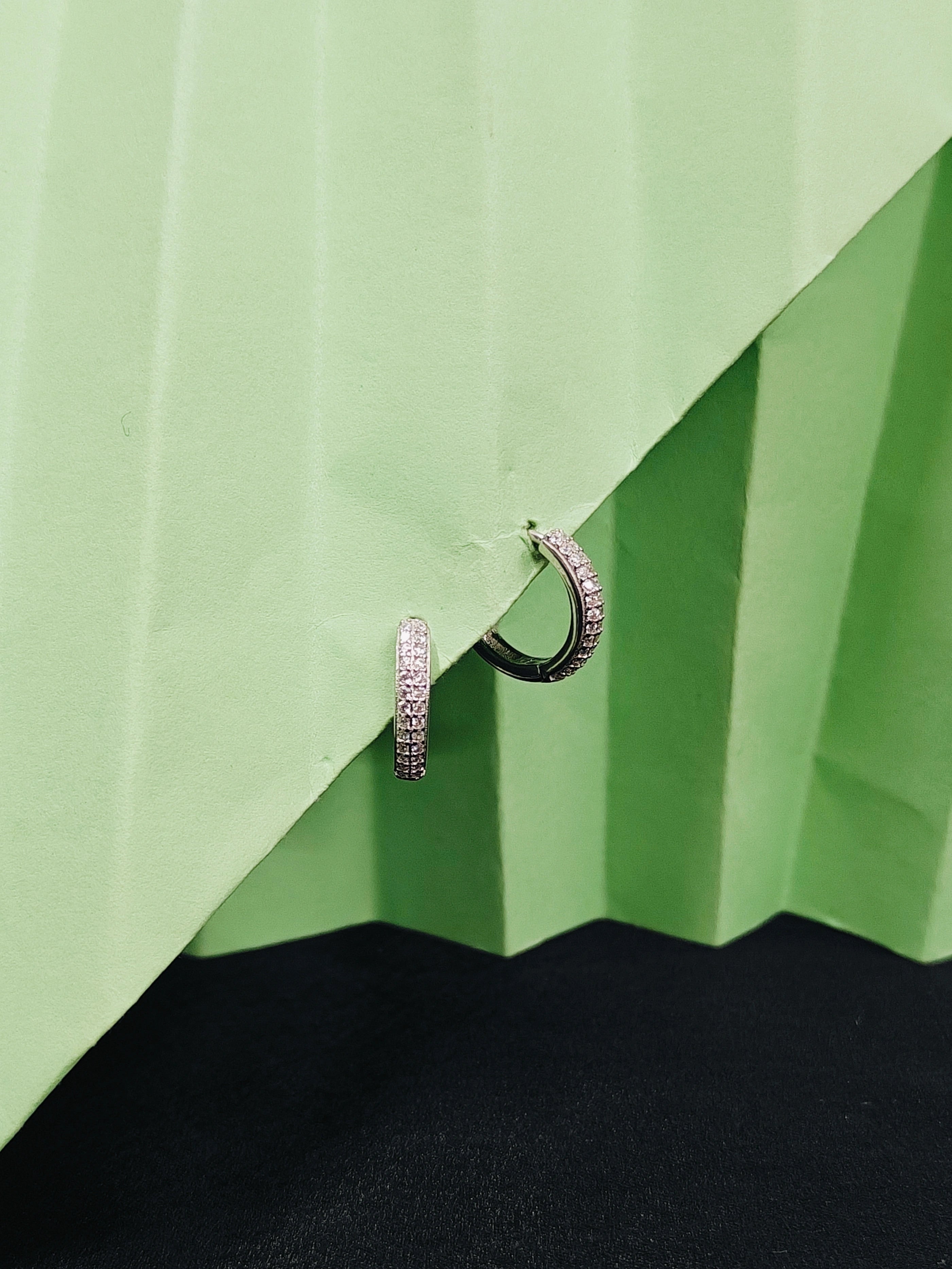 Pair of hoop earrings on a green and black textured surface