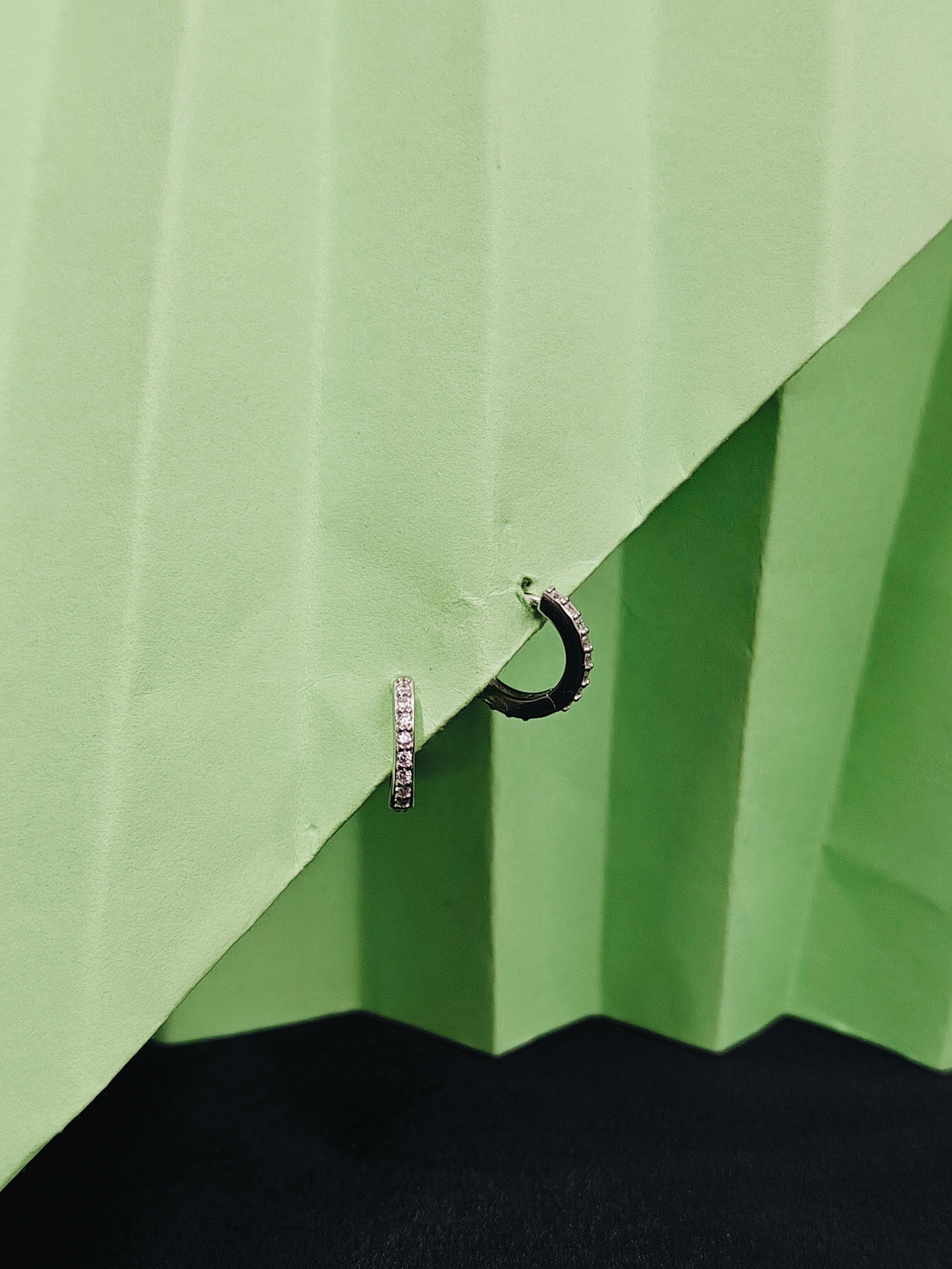 Two earrings on a green fabric background