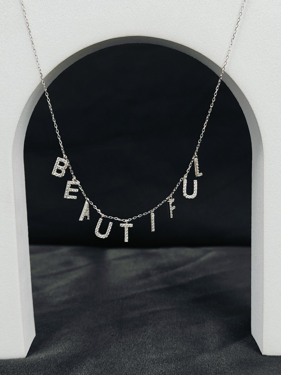 Necklace with 'BEAUTIFUL' pendant on a dark background