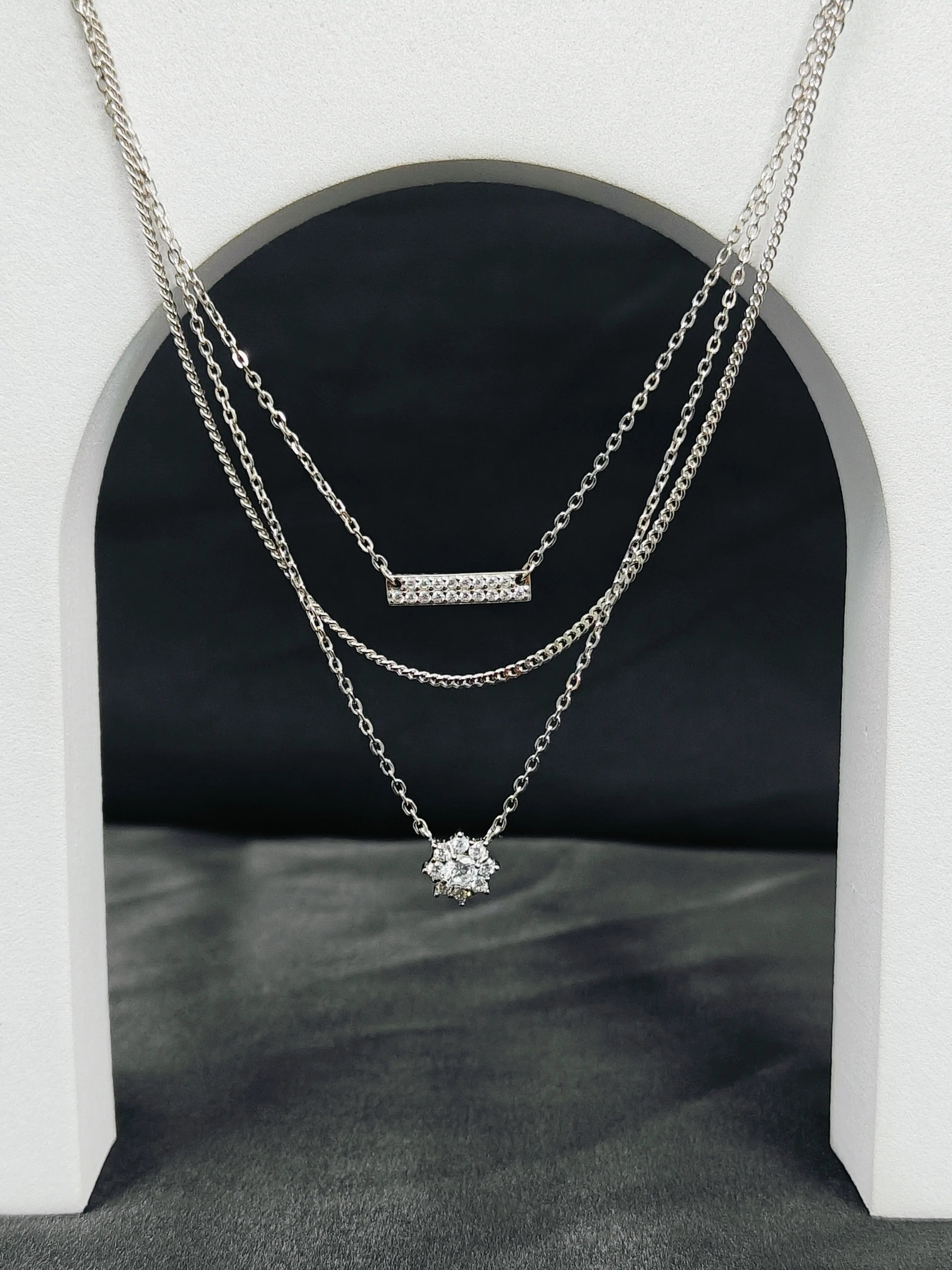 Two silver necklaces with pendants on a dark background