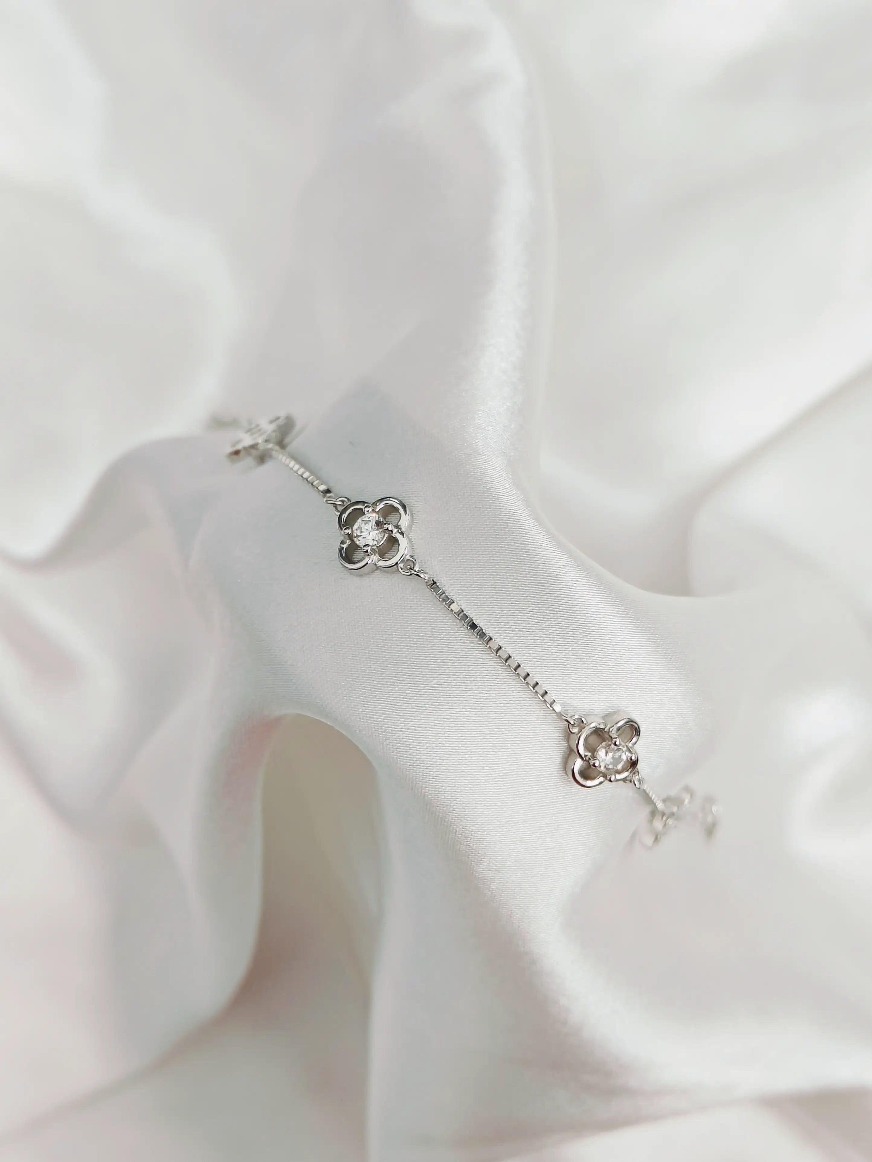 Silver floral earring on a white fabric background