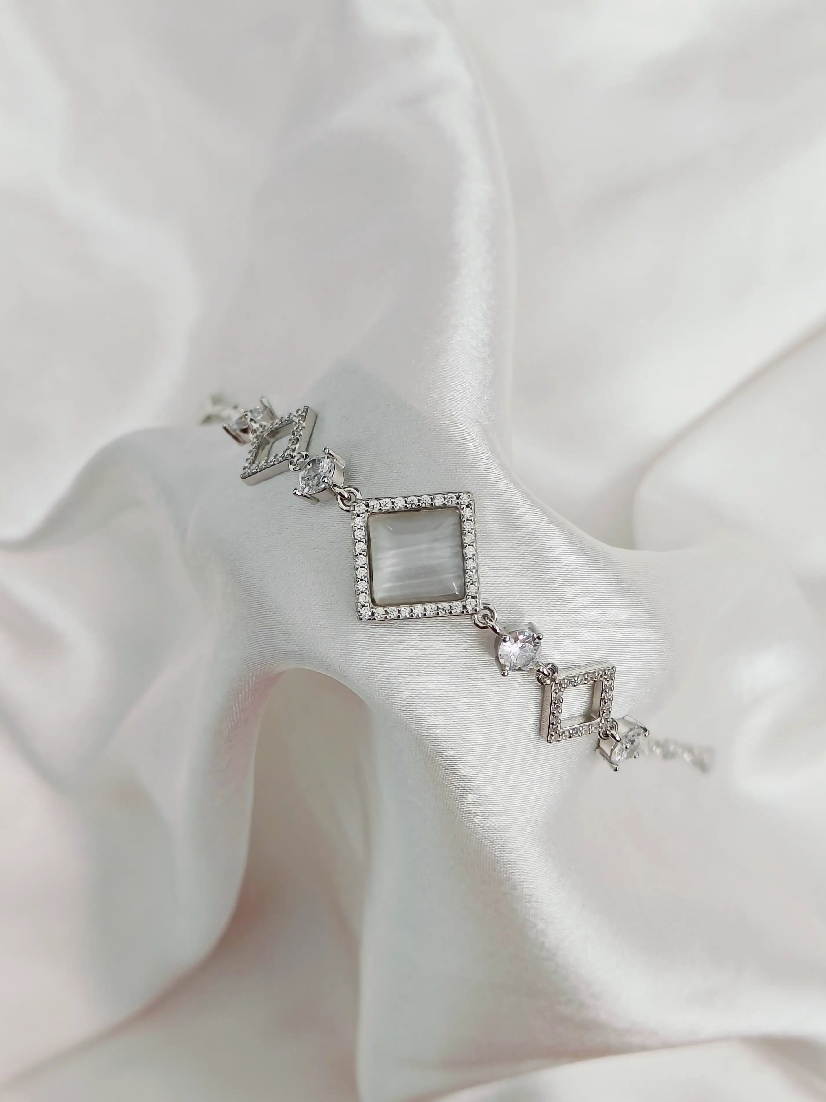 Silver bracelet with geometric design on a white fabric background