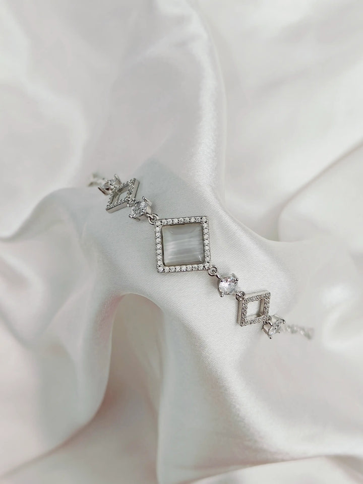 Silver bracelet with geometric design on a white fabric background