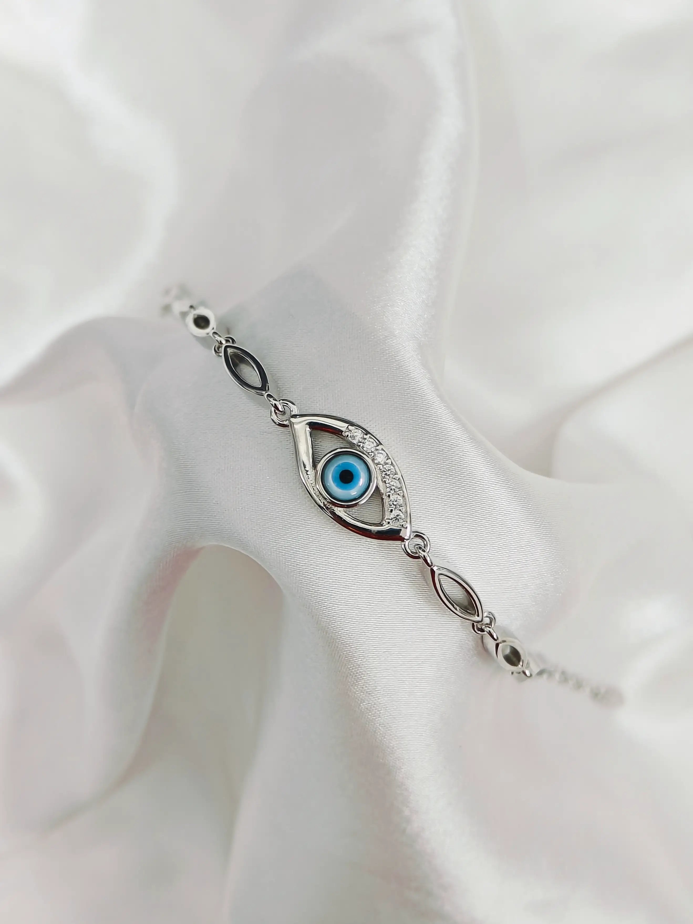Silver bracelet with eye design on a white fabric background