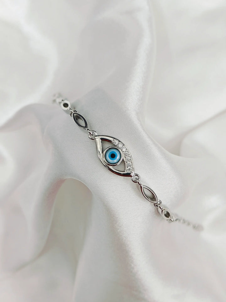 Silver bracelet with eye design on a white fabric background
