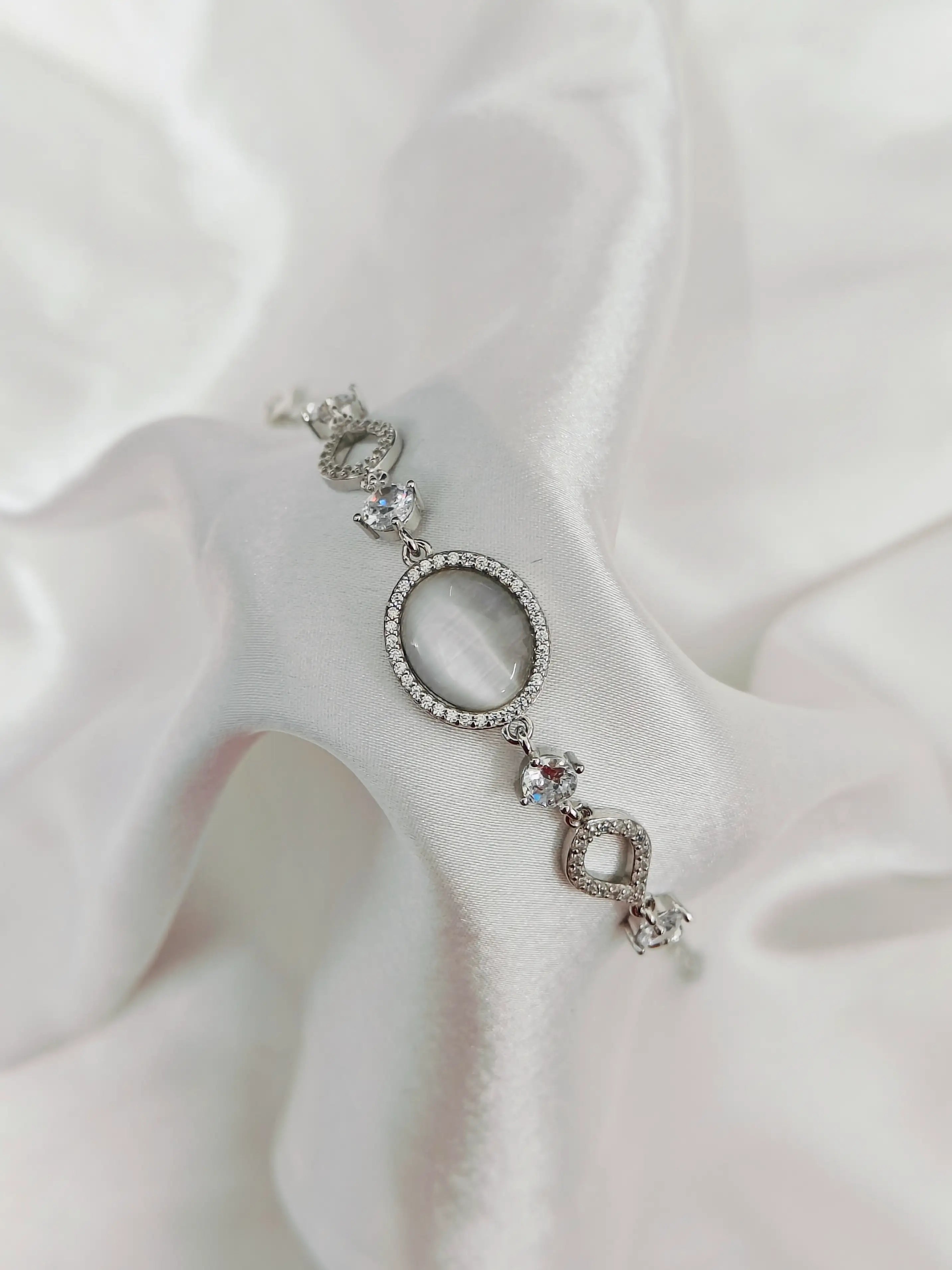 Silver earring with gemstones on a white fabric background