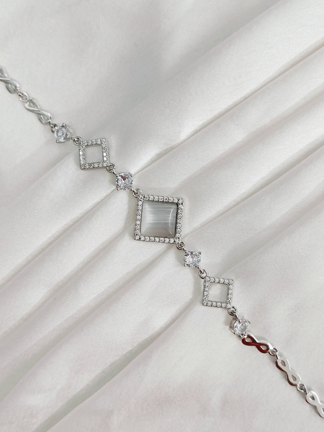 Silver bracelet with square gemstones on a white fabric background