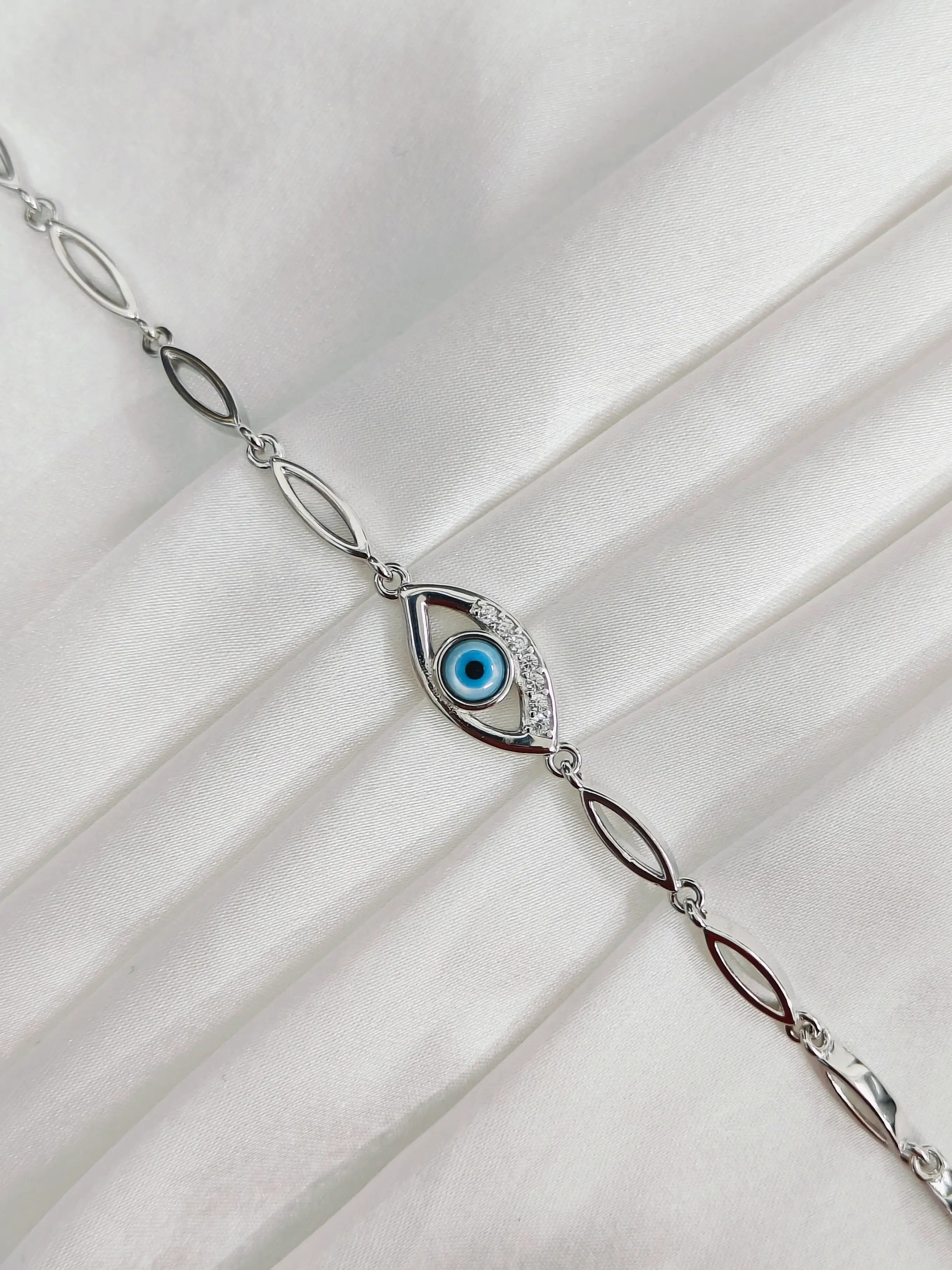 Silver bracelet with an eye design on a white fabric background