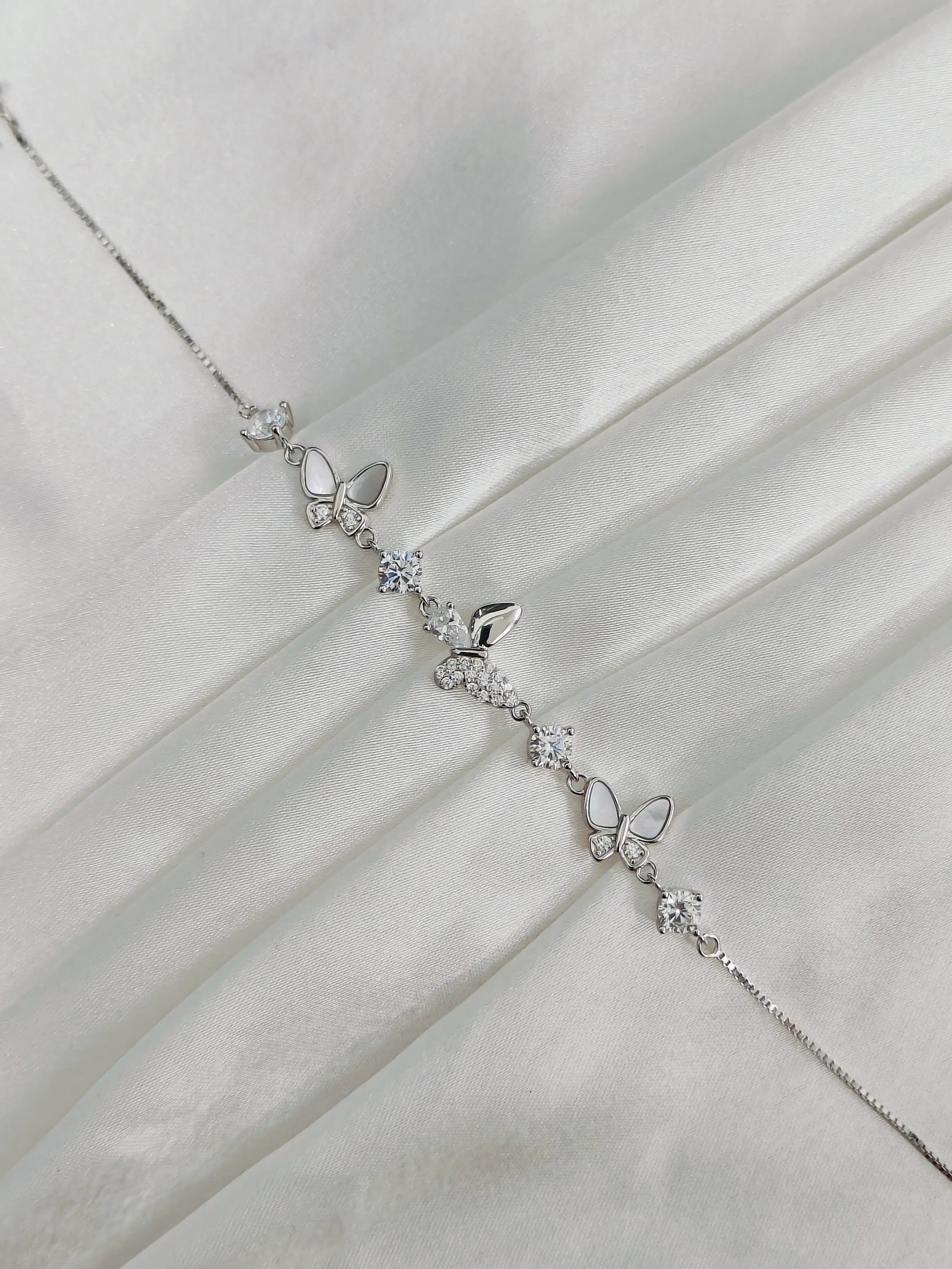 Silver butterfly necklace on a white fabric background