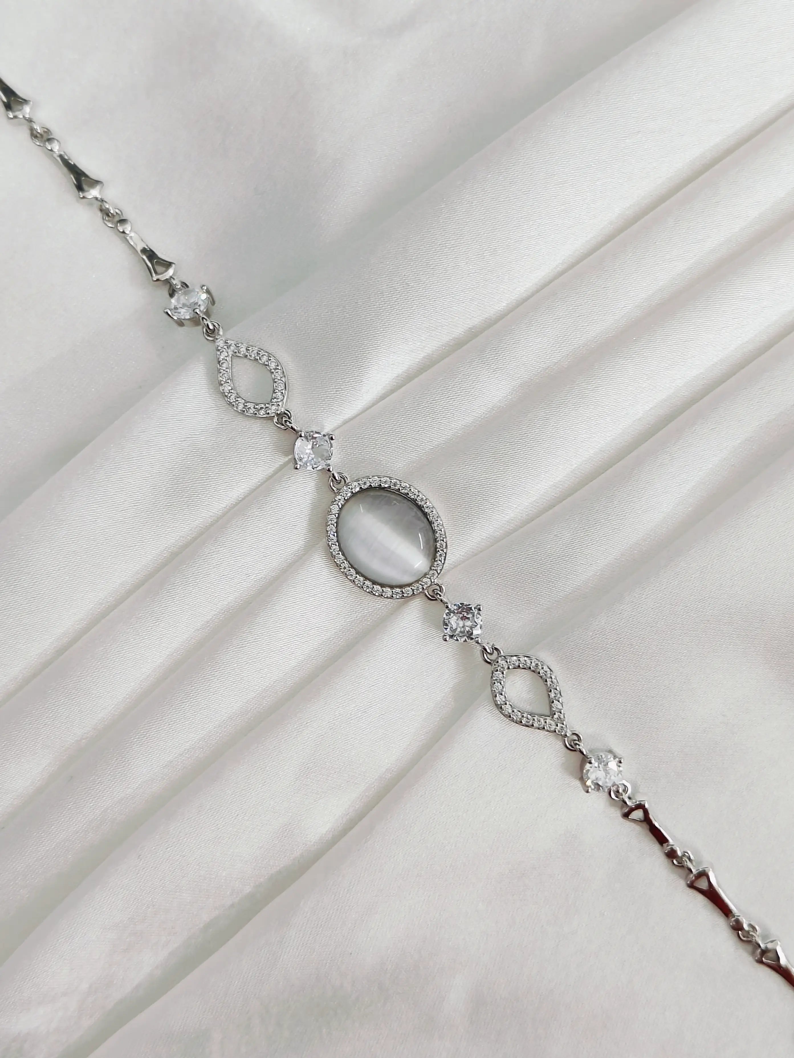 Silver bracelet with a central gemstone on a white fabric background