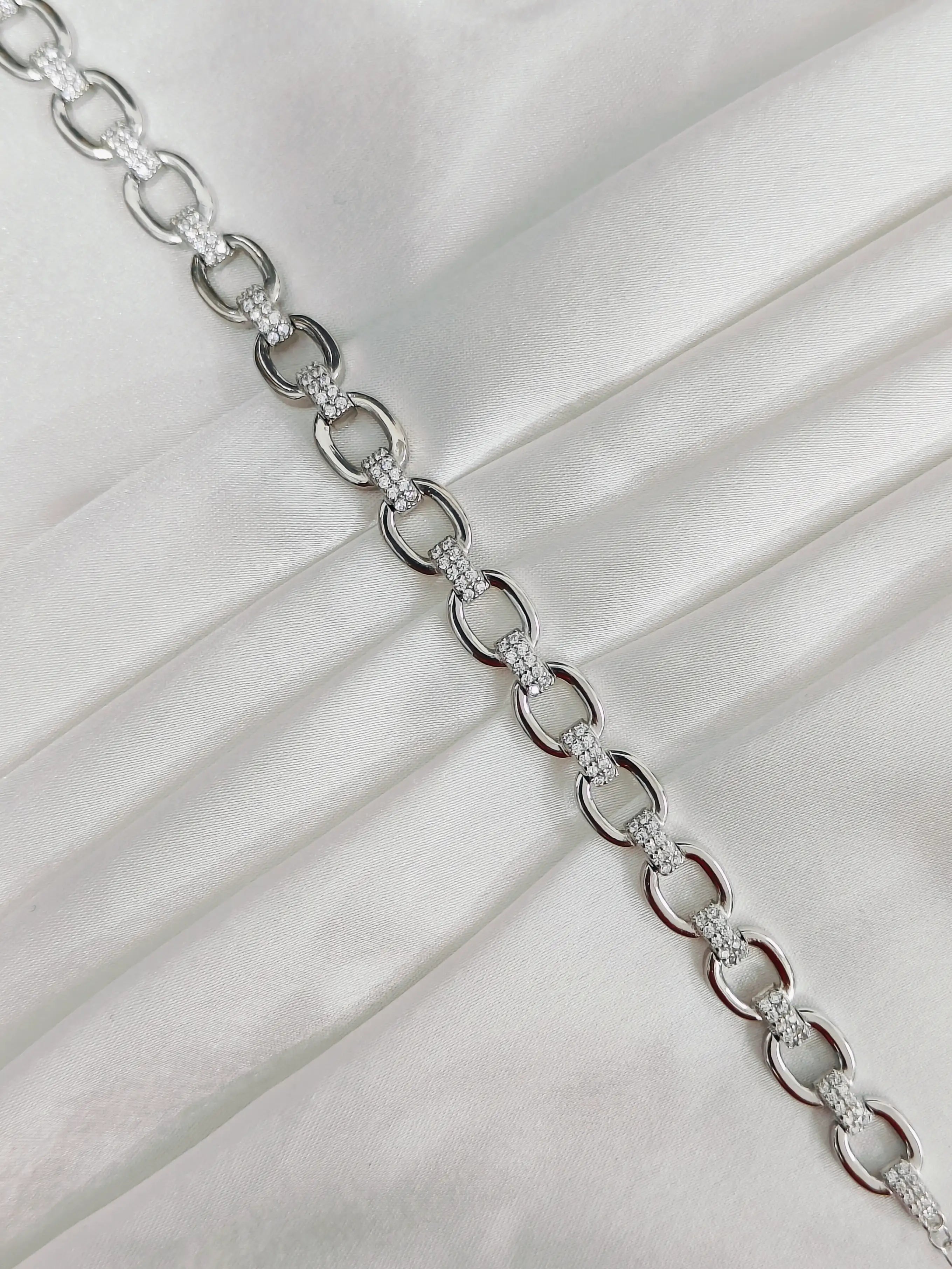 Silver chain necklace on a white fabric background