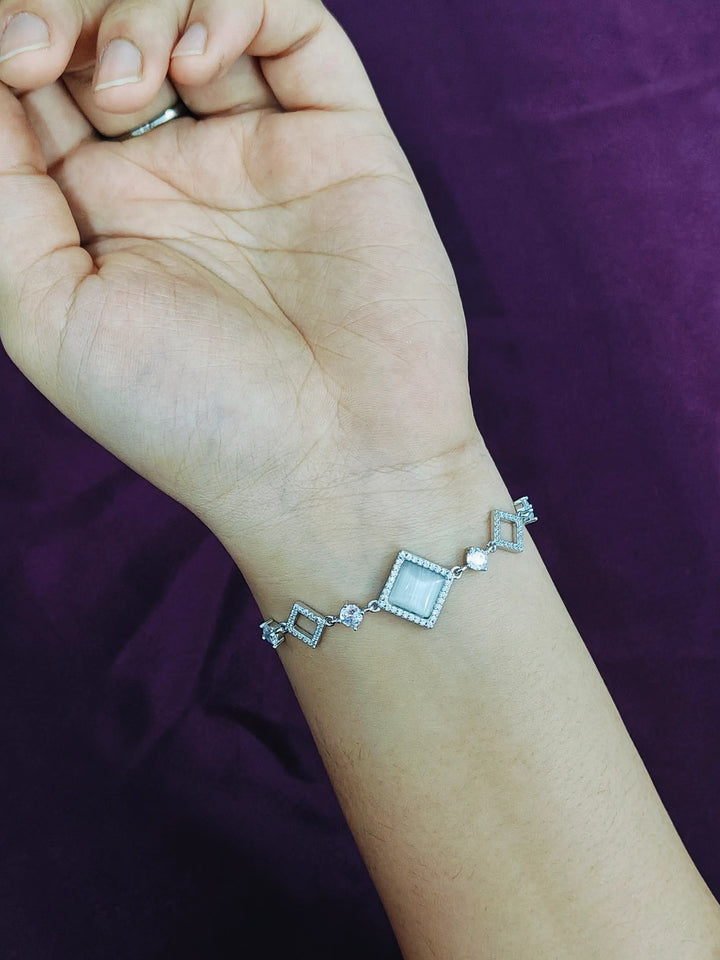 Silver bracelet on a wrist with a purple background