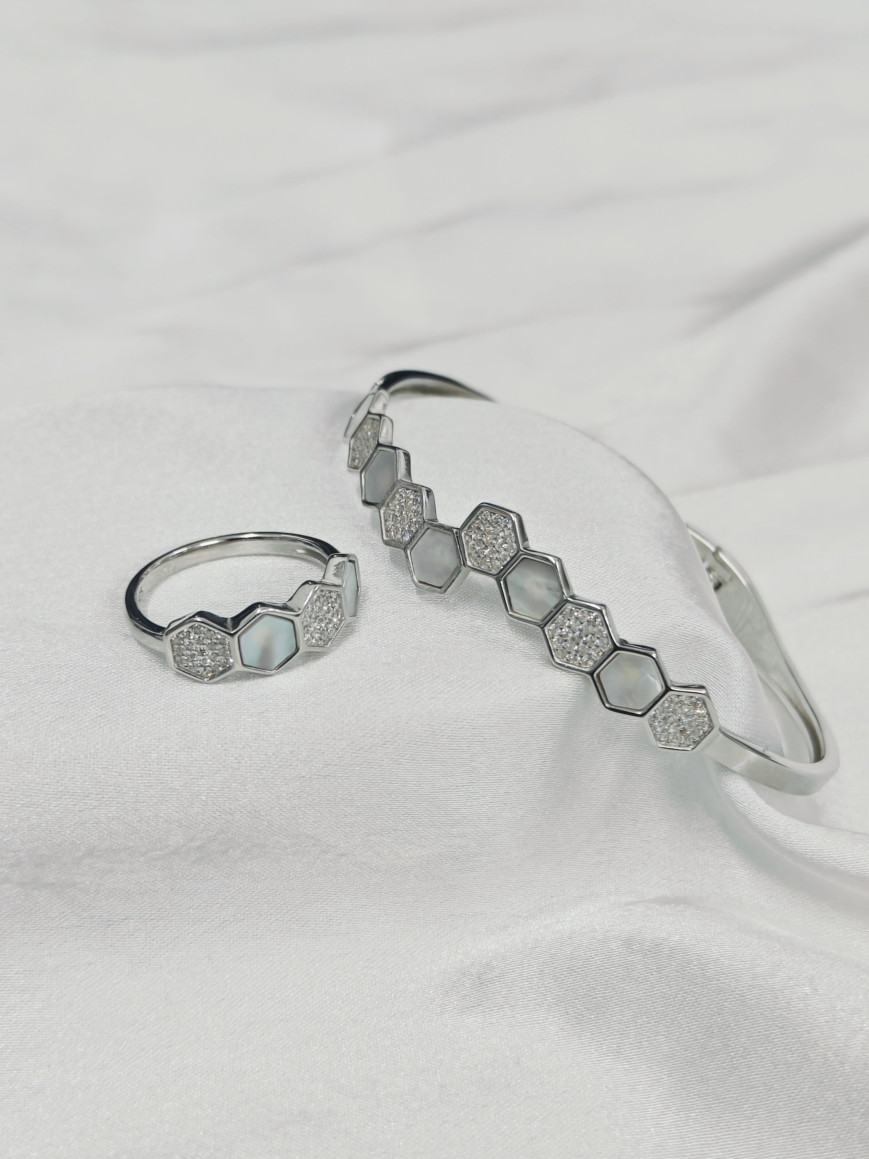 Silver ring and bracelet with hexagonal patterns on a white fabric background