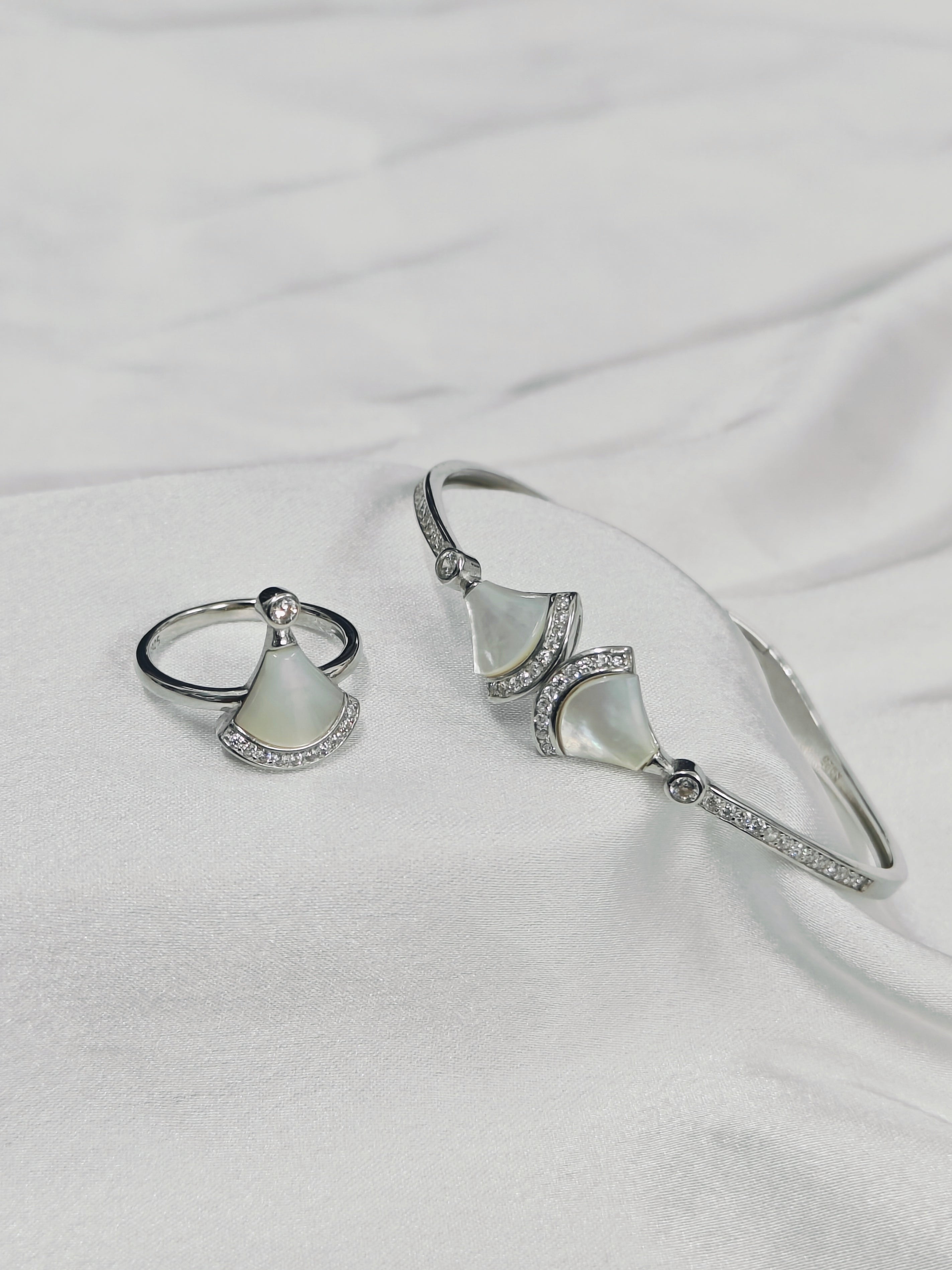 Silver ring and bracelet set on a white fabric background