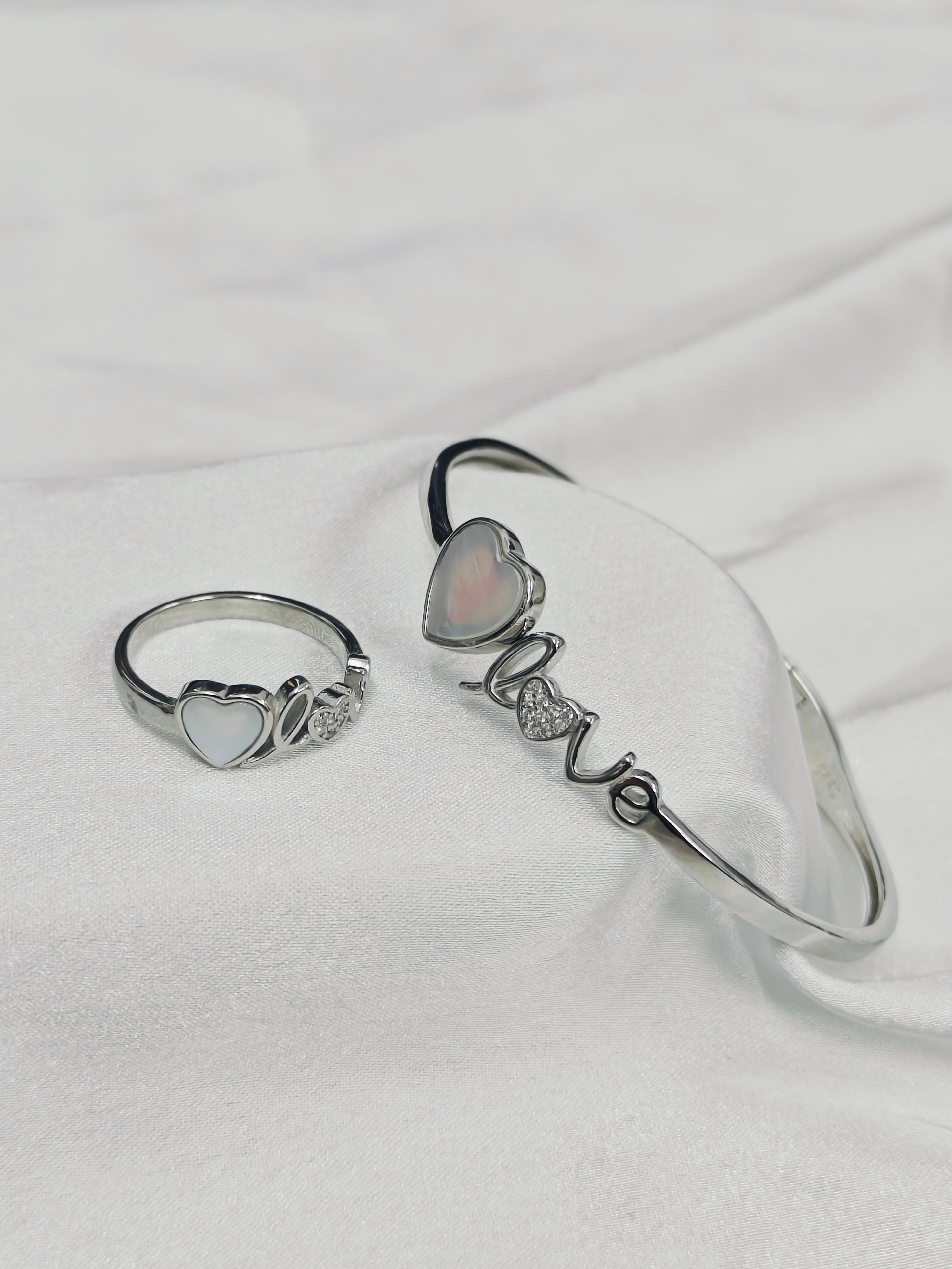 Silver ring and bracelet set on a white fabric background