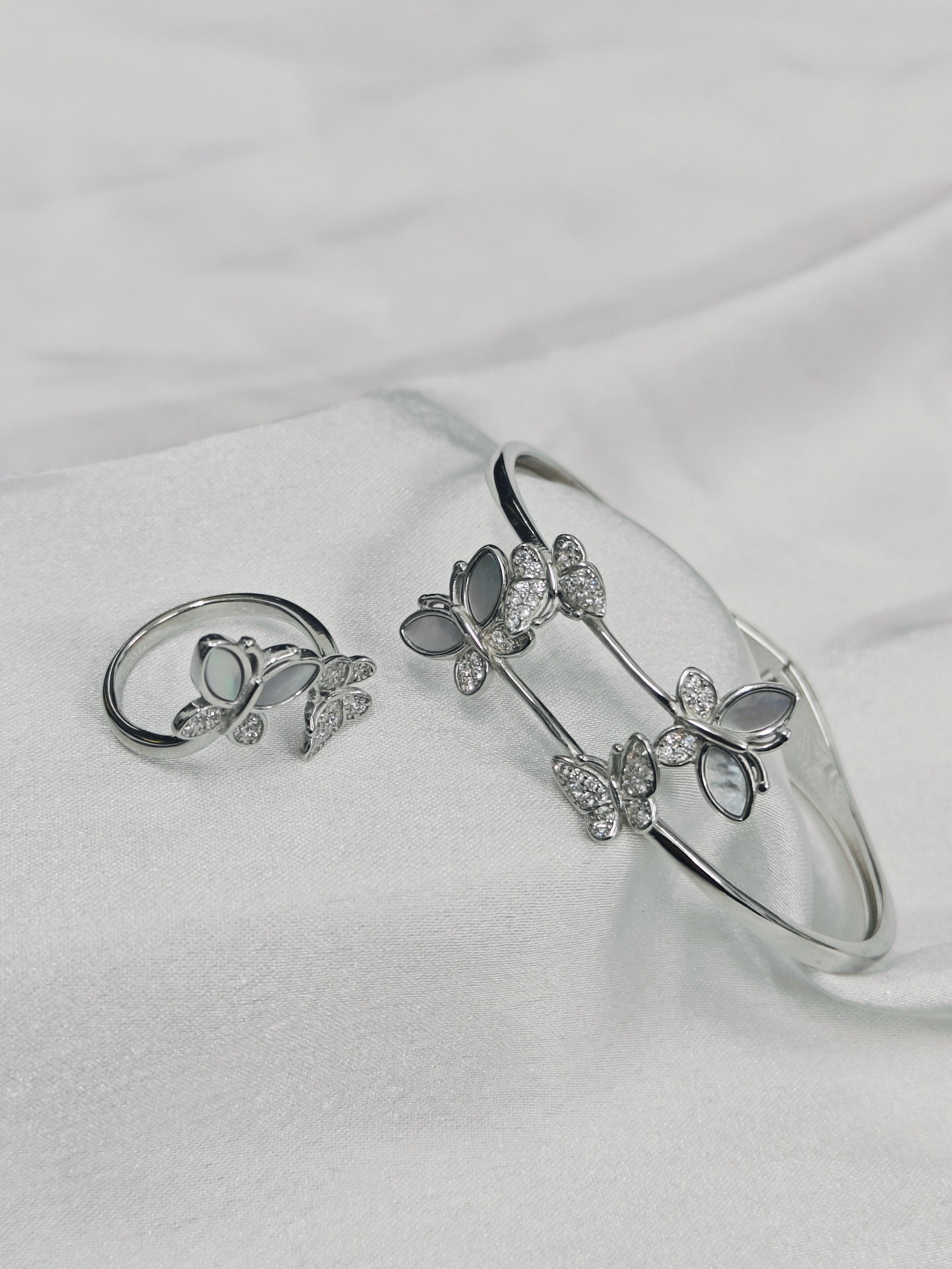 Silver bracelet and ring set on a white fabric background