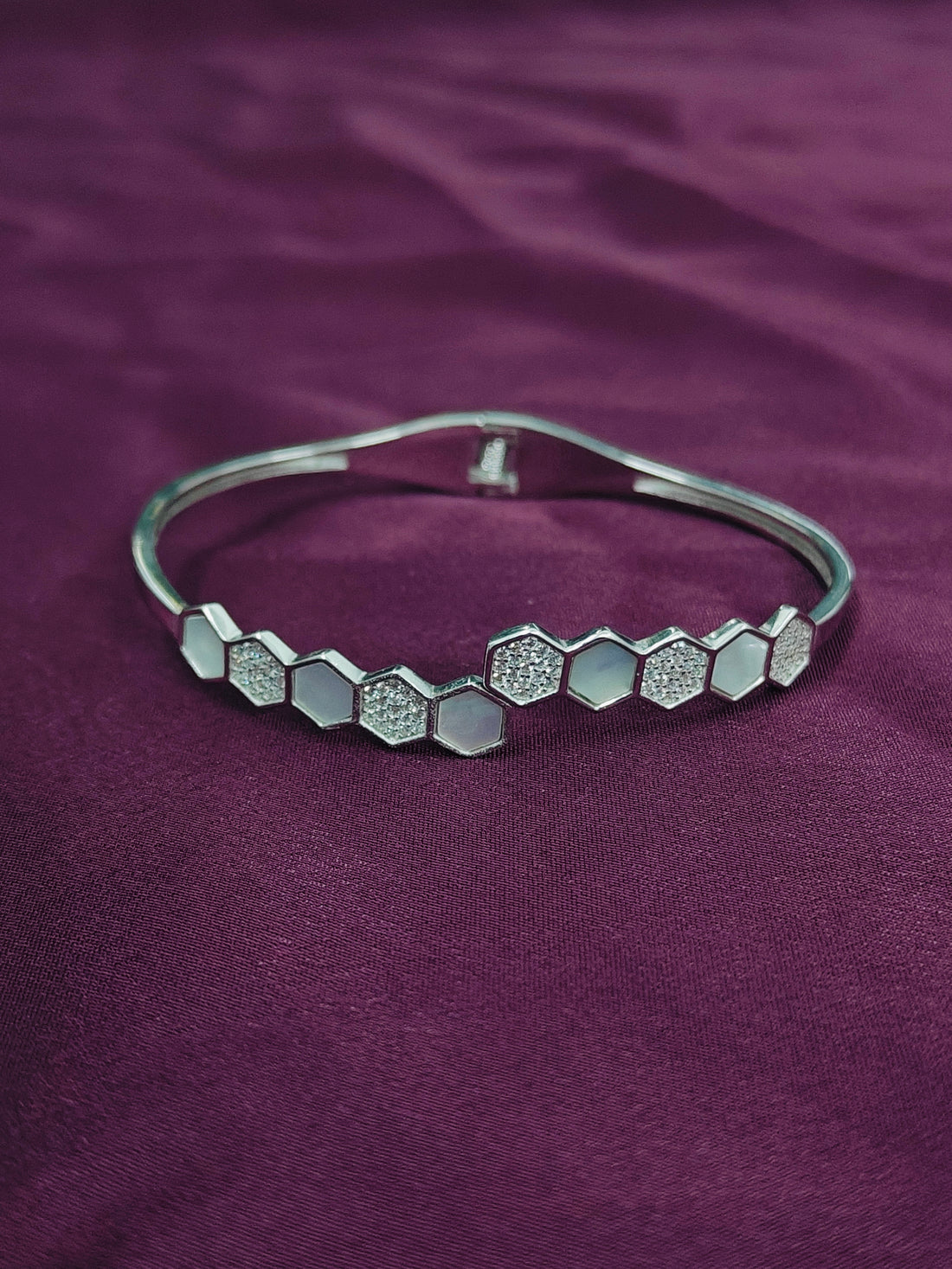 Silver bracelet with hexagonal pattern on a purple fabric background