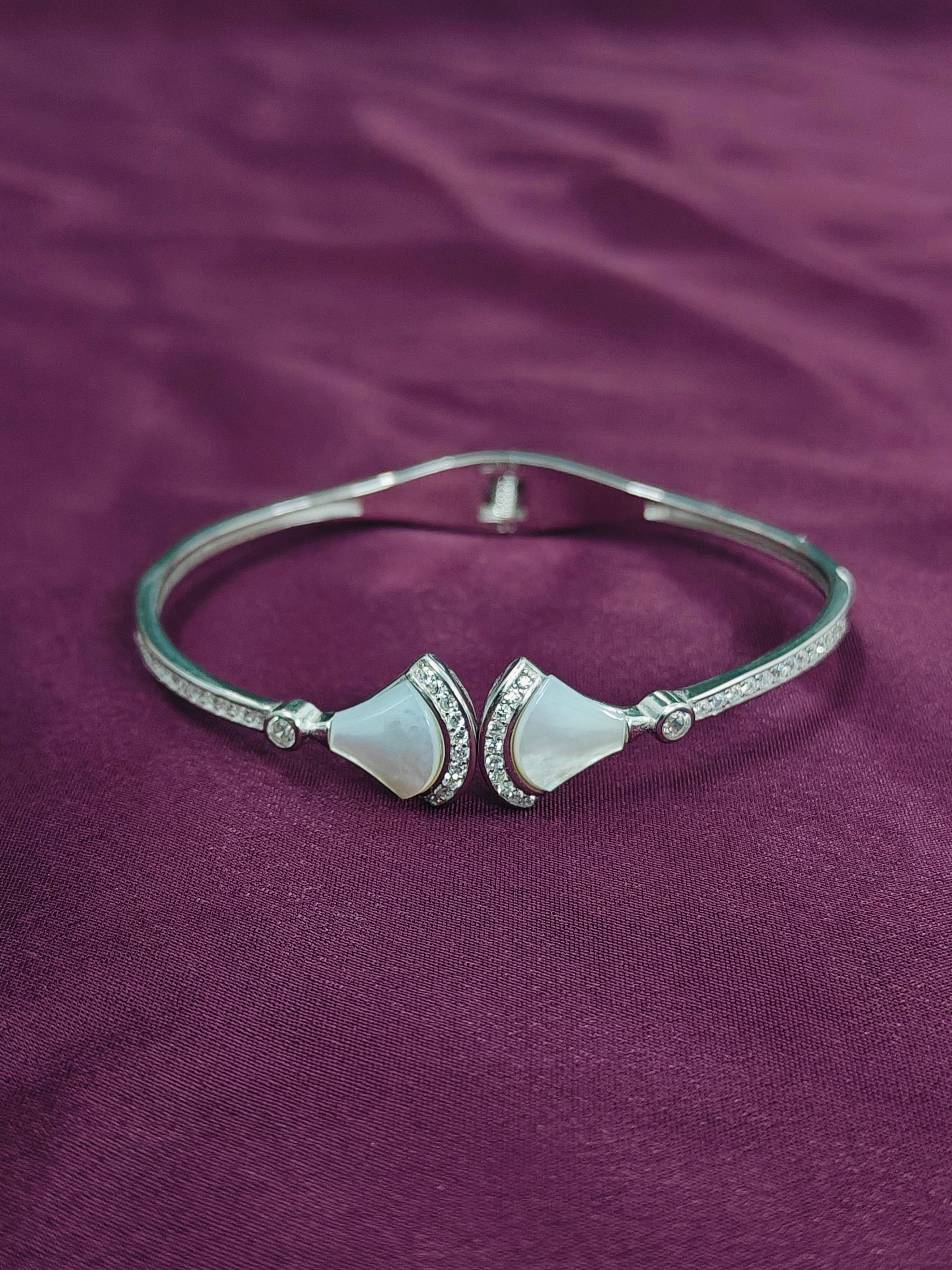Silver bracelet with two white stones on a purple fabric background