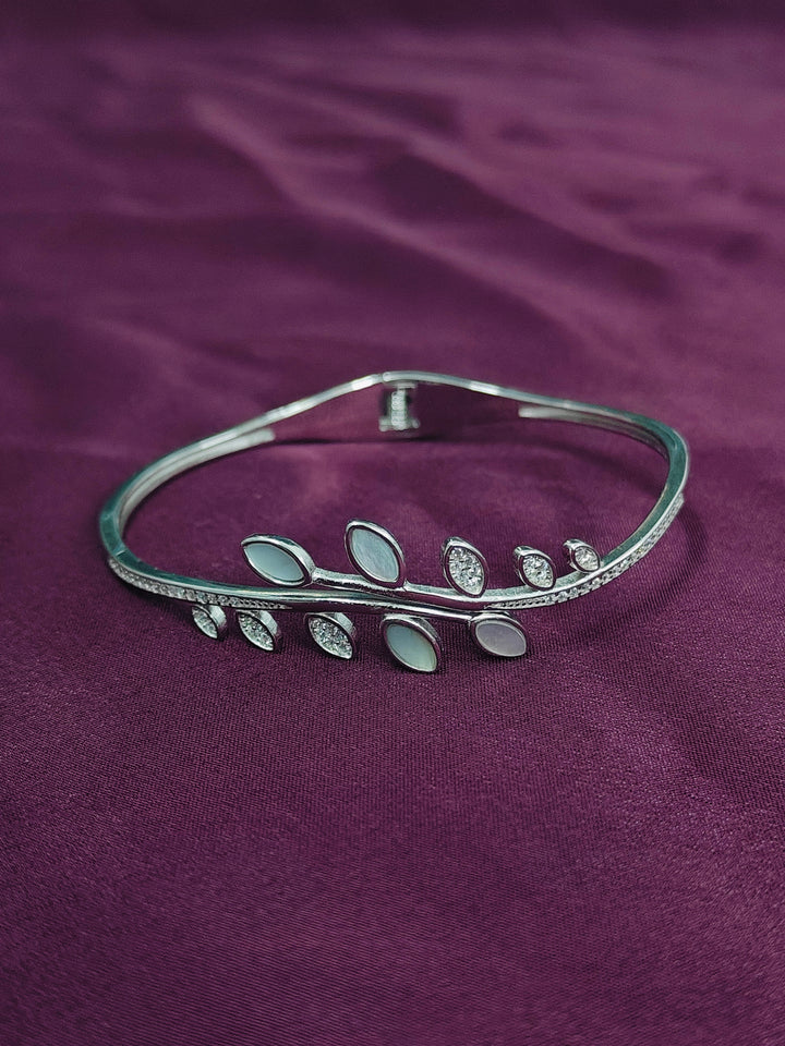 Silver bracelet with leaf design on a purple fabric background