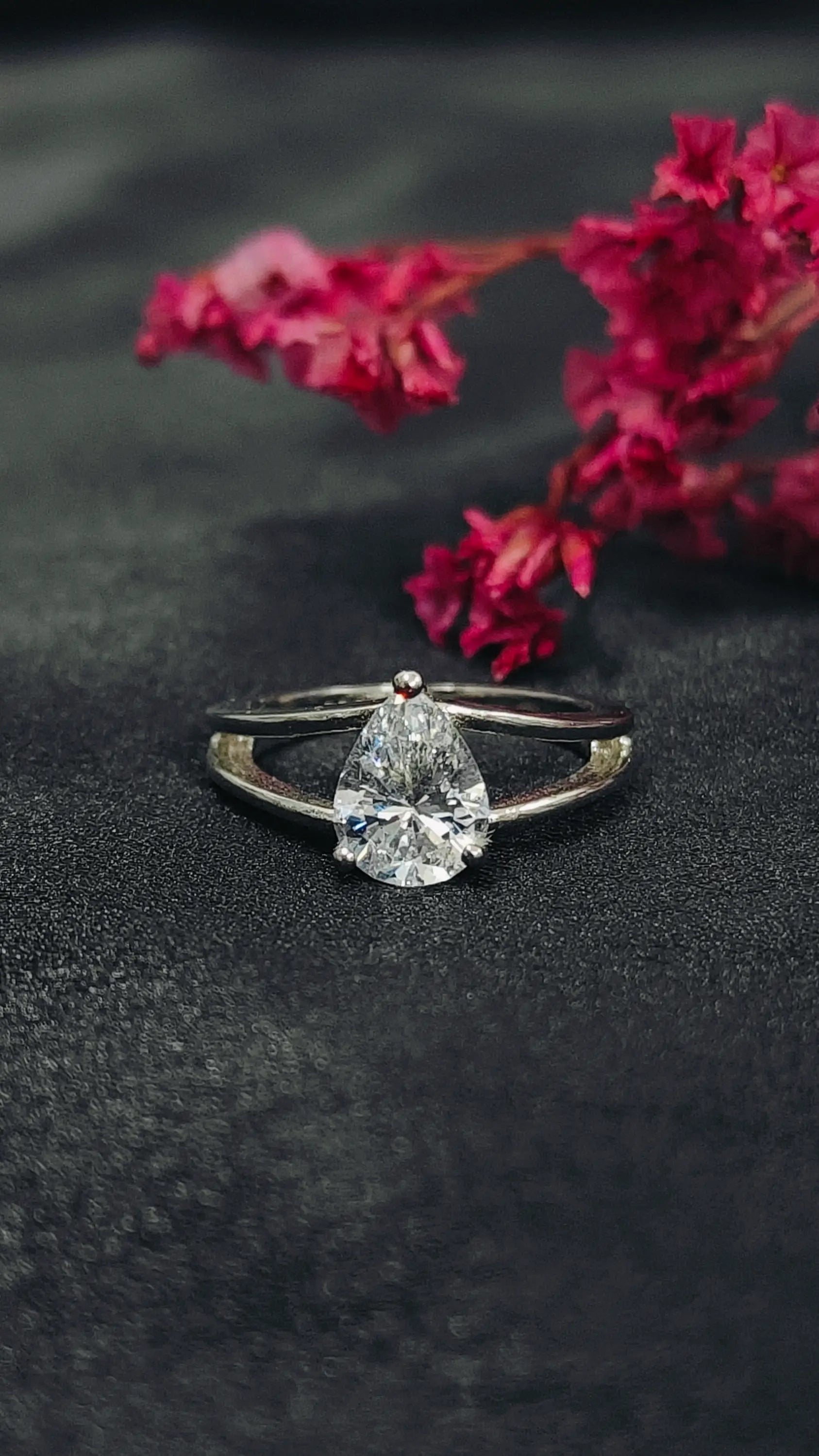 Diamond ring on a dark surface with red flowers