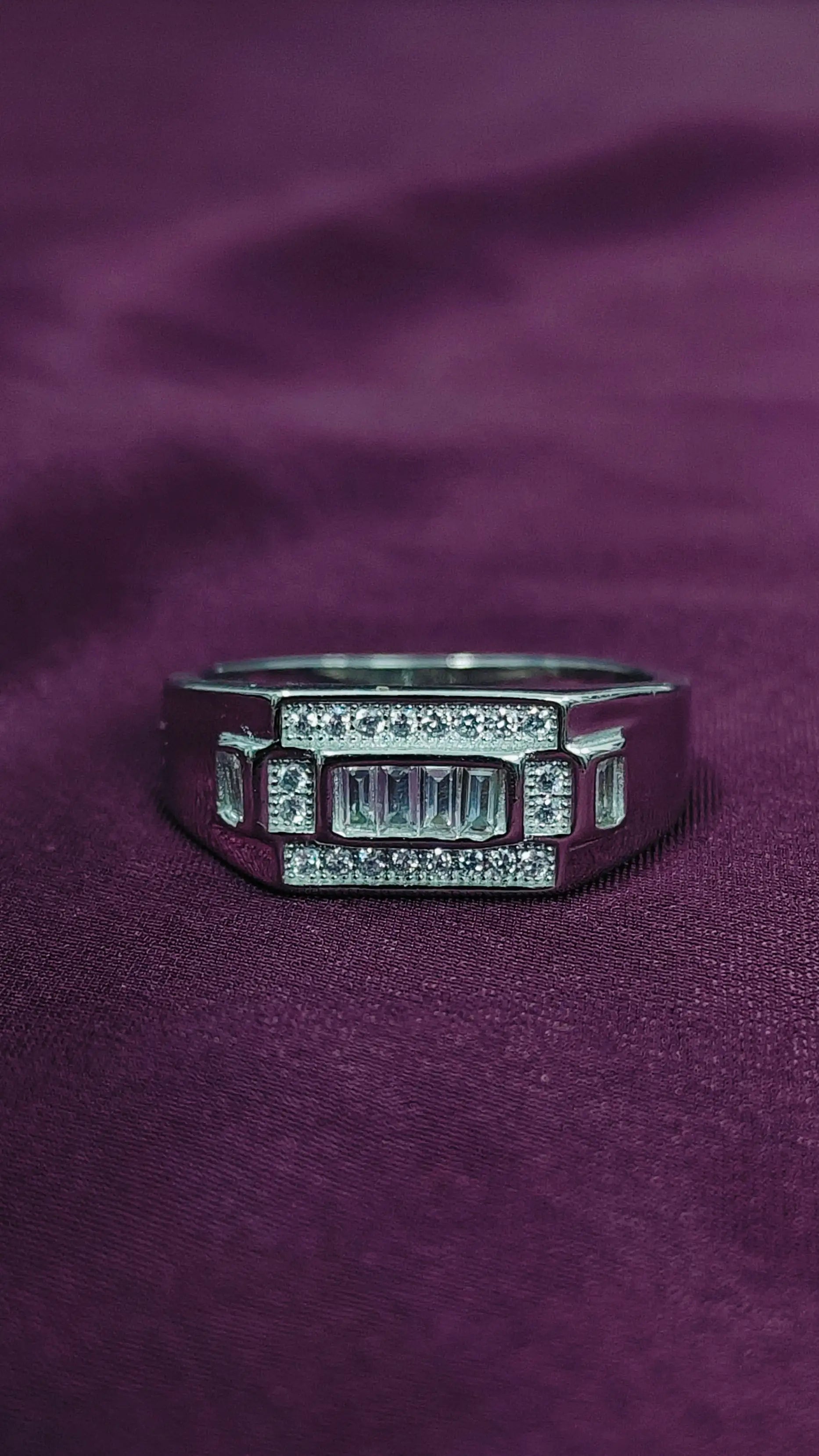 Silver ring with gemstones on a purple fabric background