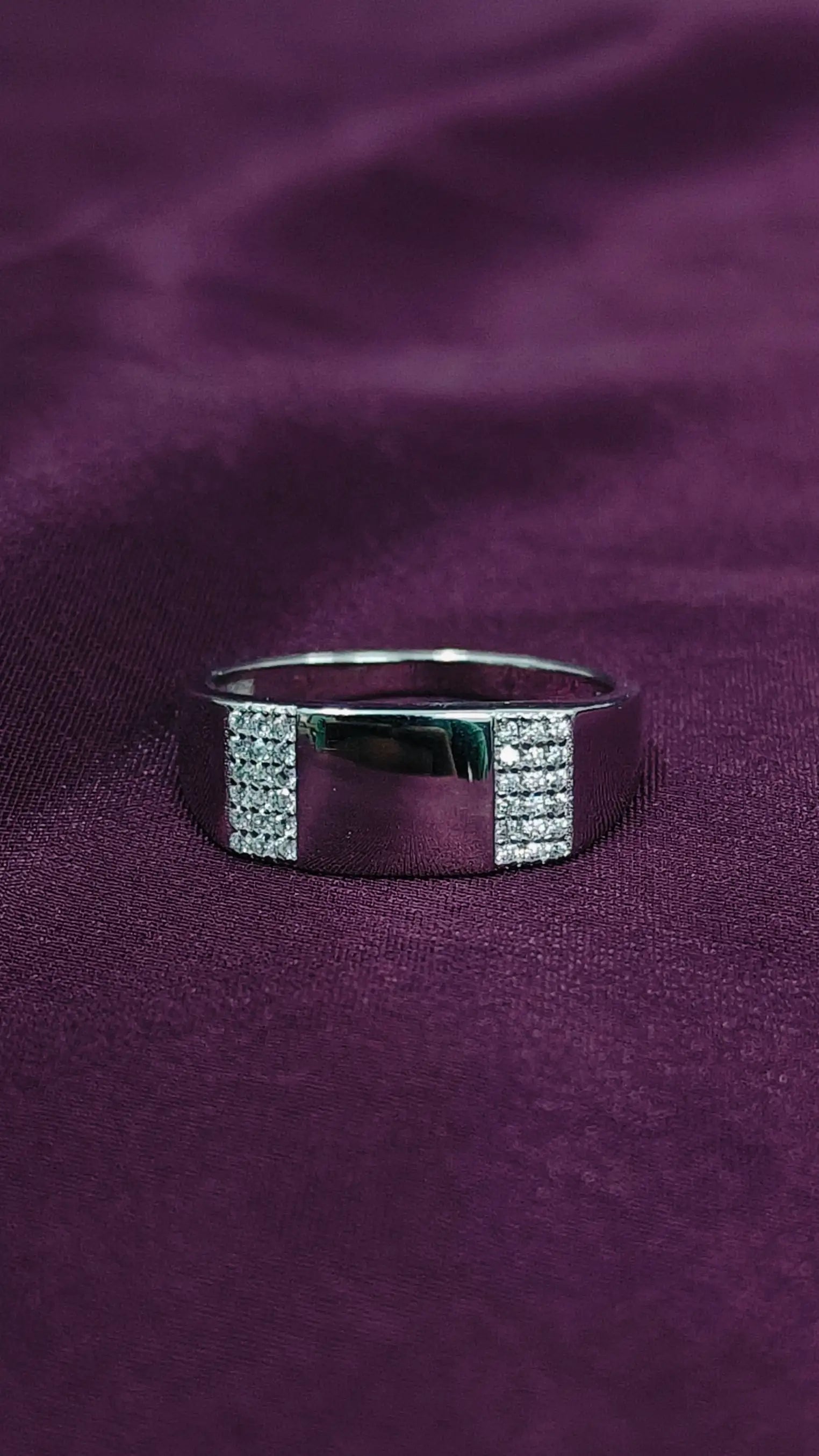 Silver ring with embedded stones on a purple fabric background